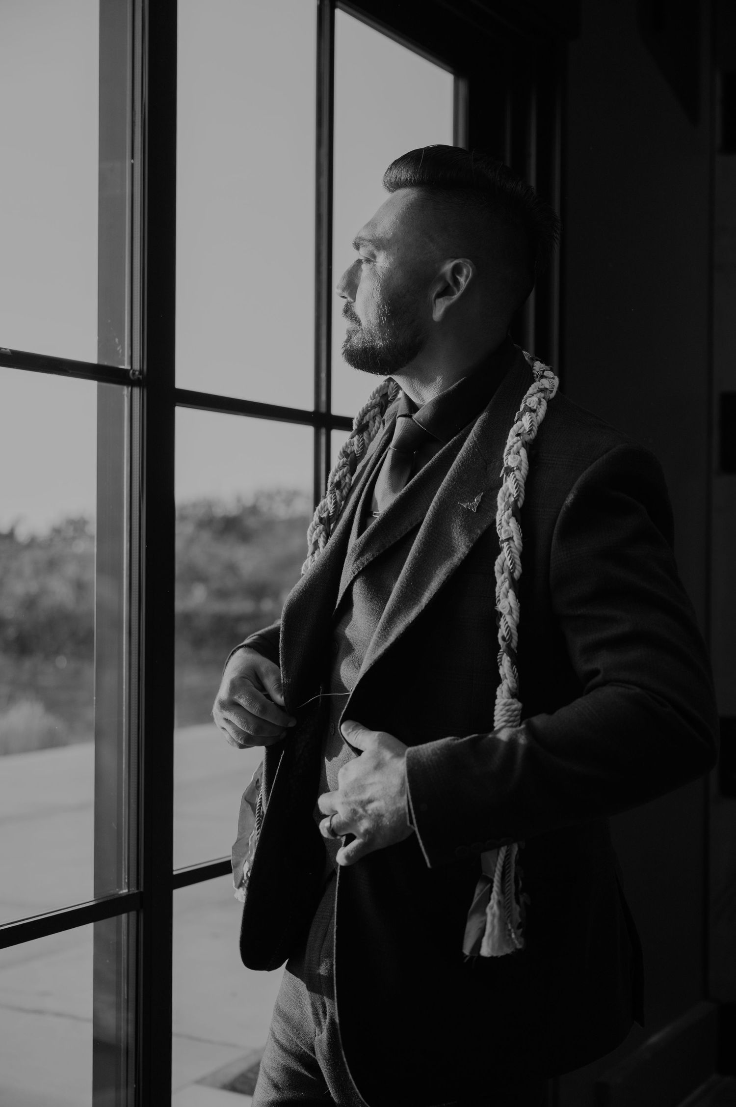 Black and white photos of someone by a window in formal attire.