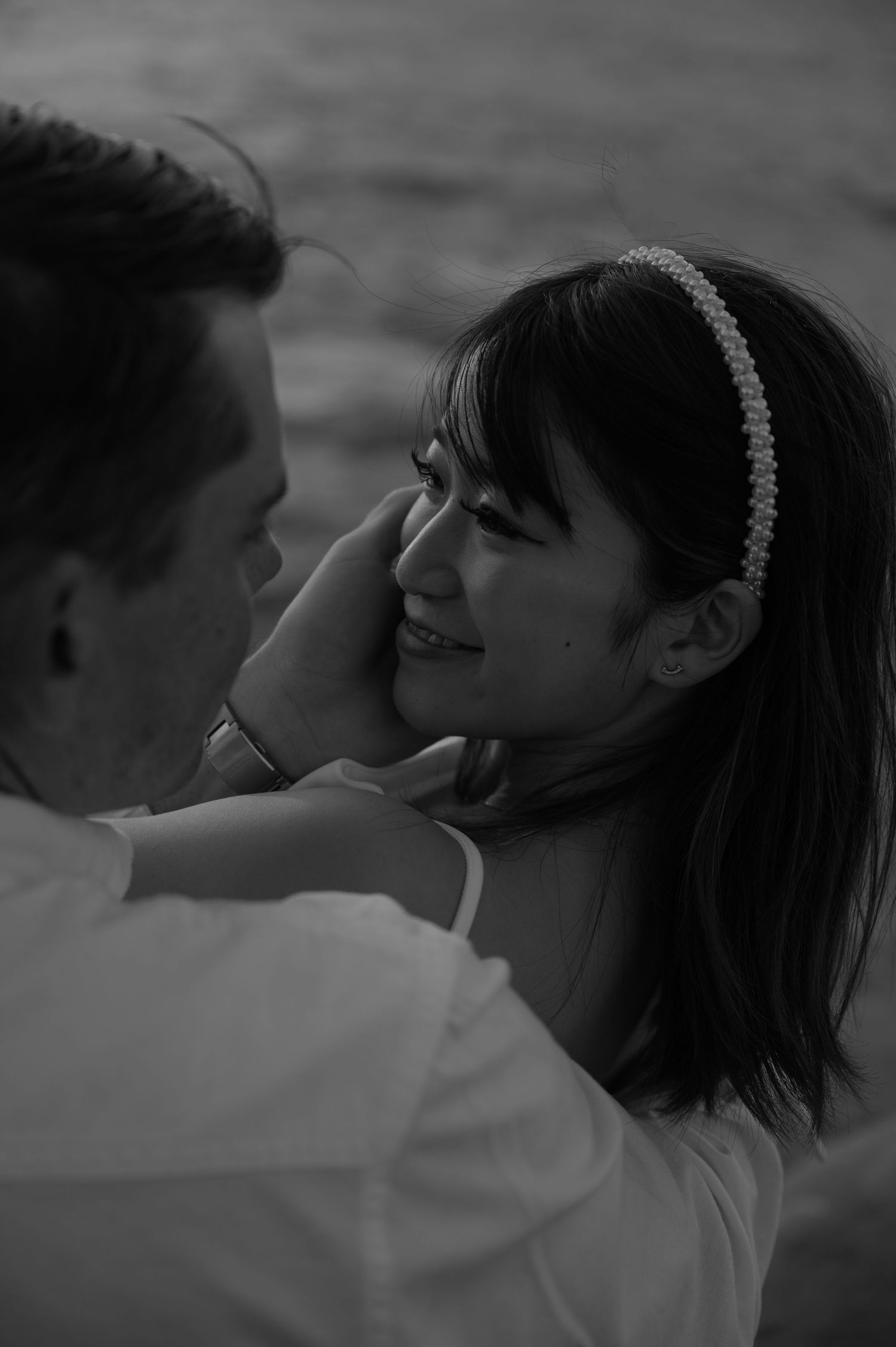 A romantic black and white photo sequence of a couple sharing an intimate kiss by the ocean.