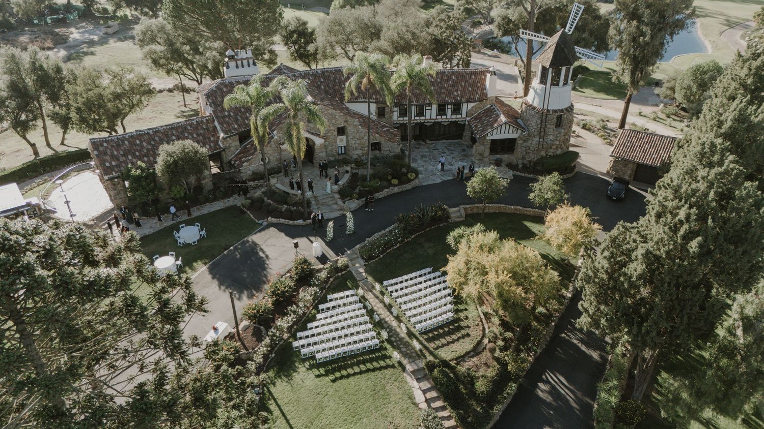 Aerial view of a scenic outdoor wedding venue with palm trees and elegant seating arrangements.