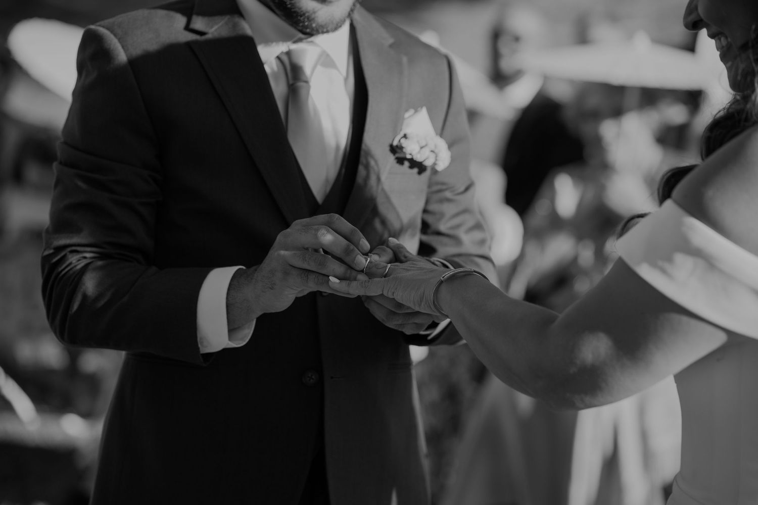 Groom places wedding ring on brides finger during elegant ceremony in black and white.
