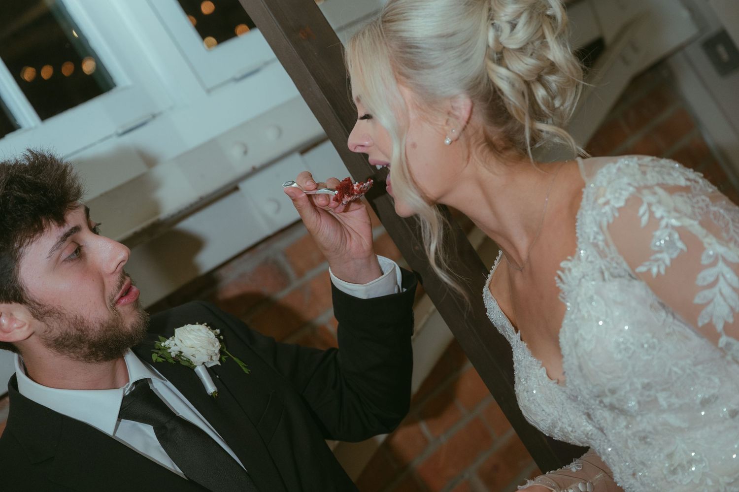 Groom feeding bride a piece of food at their wedding reception in an elegant venue.