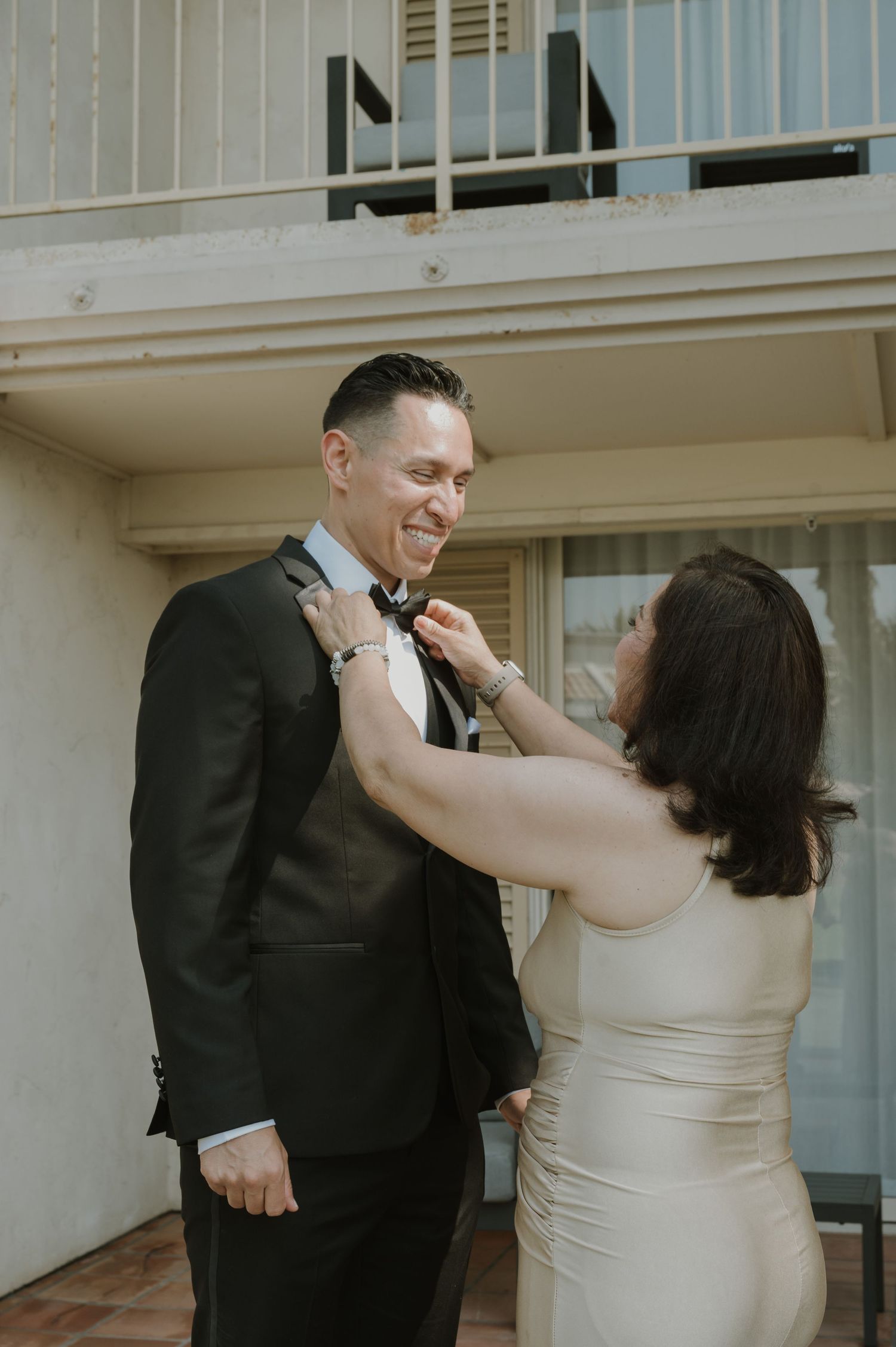 Wedding preparation moment as couple helps with formal attire adjustments.