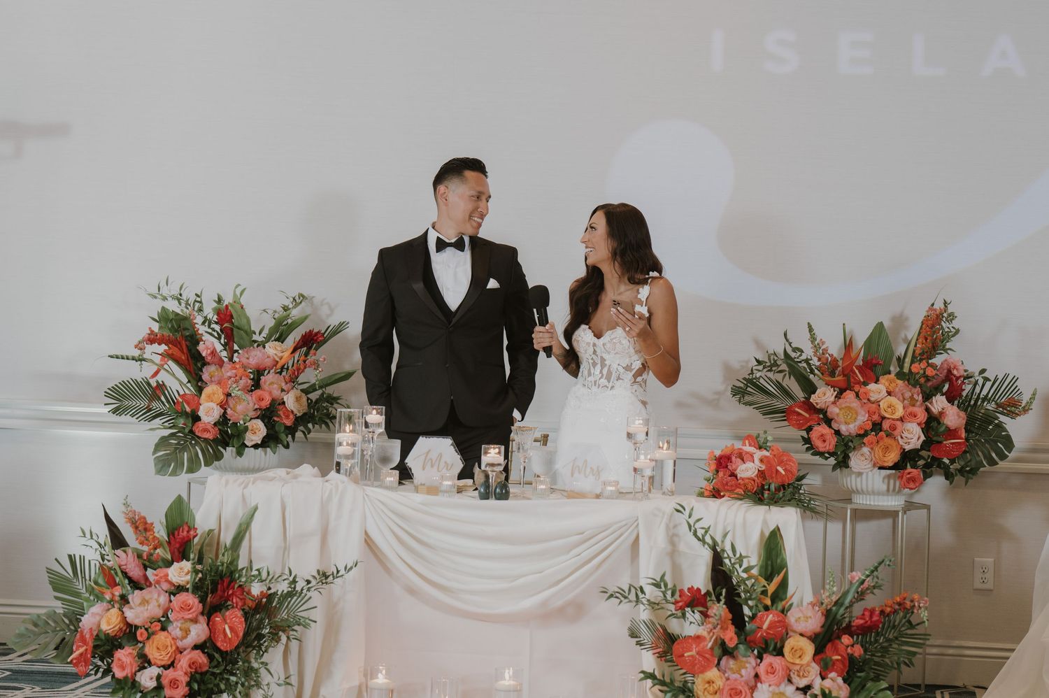 Wedding venue decorated with coral and white floral arrangements against a minimalist white backdrop.