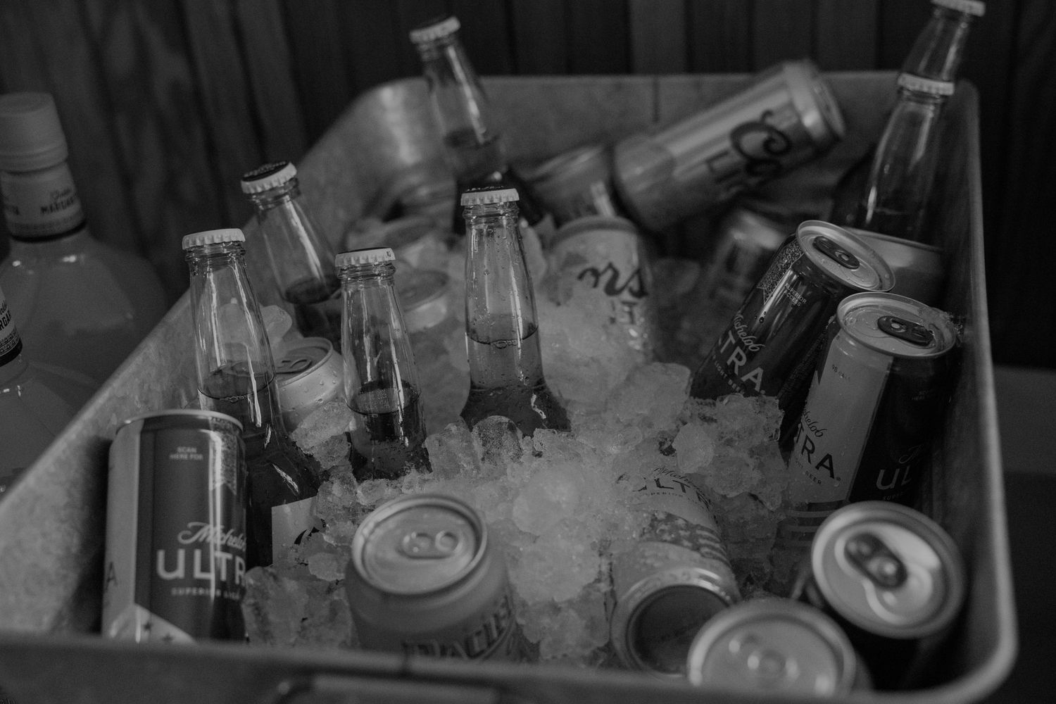Assorted beverages chilling in ice at an outdoor event bar setup.