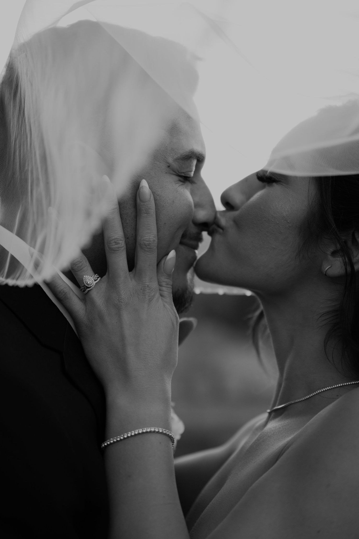 Black and white close-up of tender moment between newlyweds with bride's hand on groom's face.