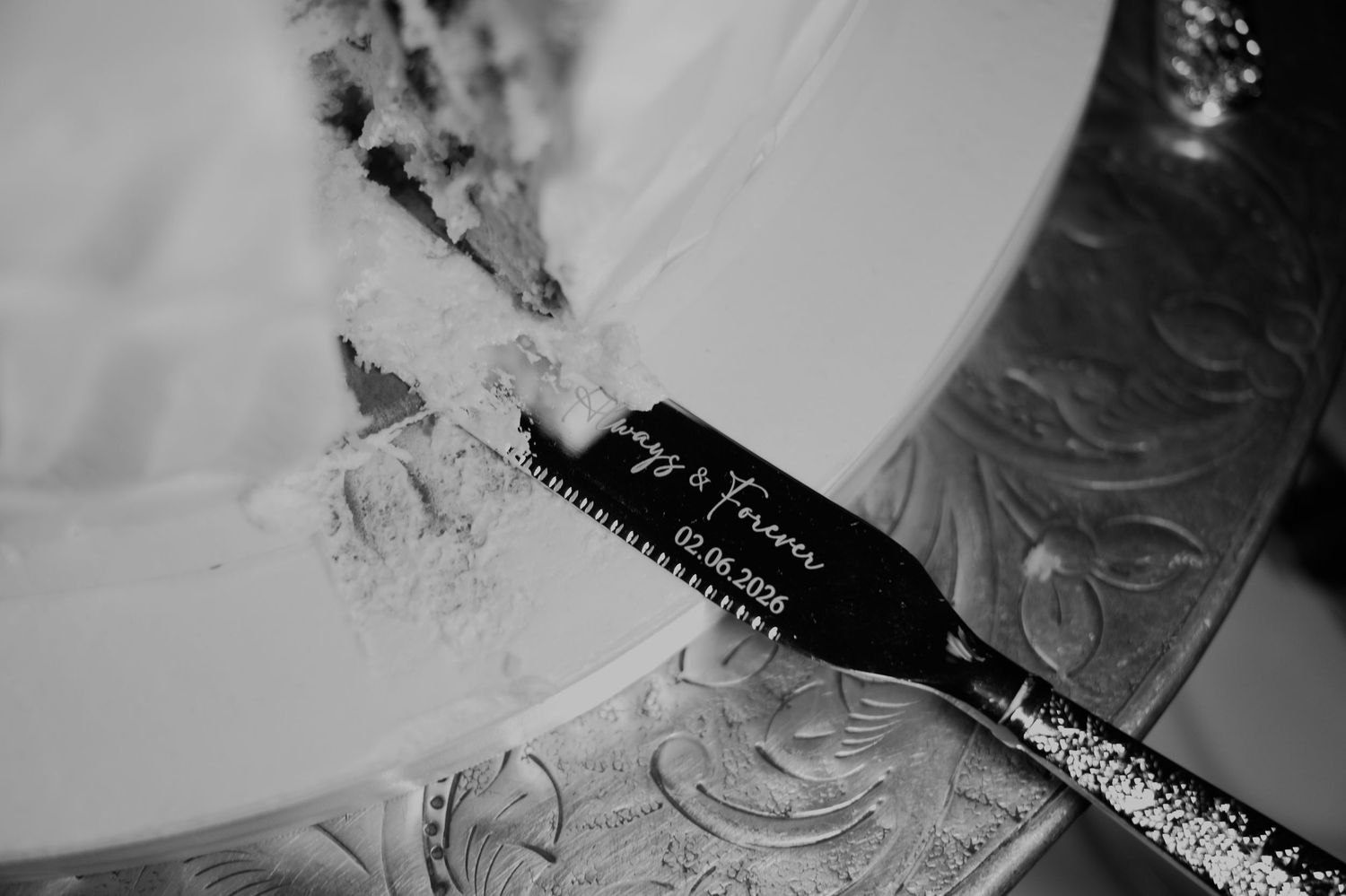 Black and white close-up of engraved wedding cake cutting set reading Forever on ornate silver server.