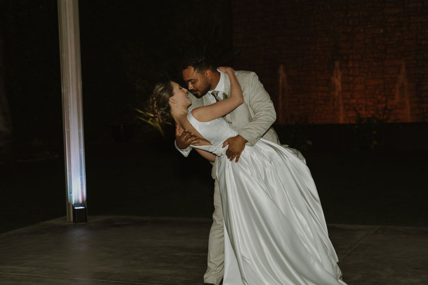 Bride and groom share romantic first dance dip at elegant wedding reception venue.