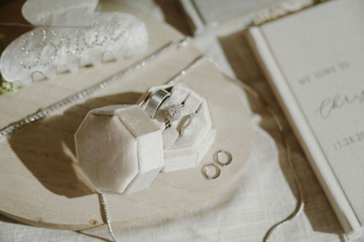 Wedding rings and delicate details arranged on white paper with soft shadows.