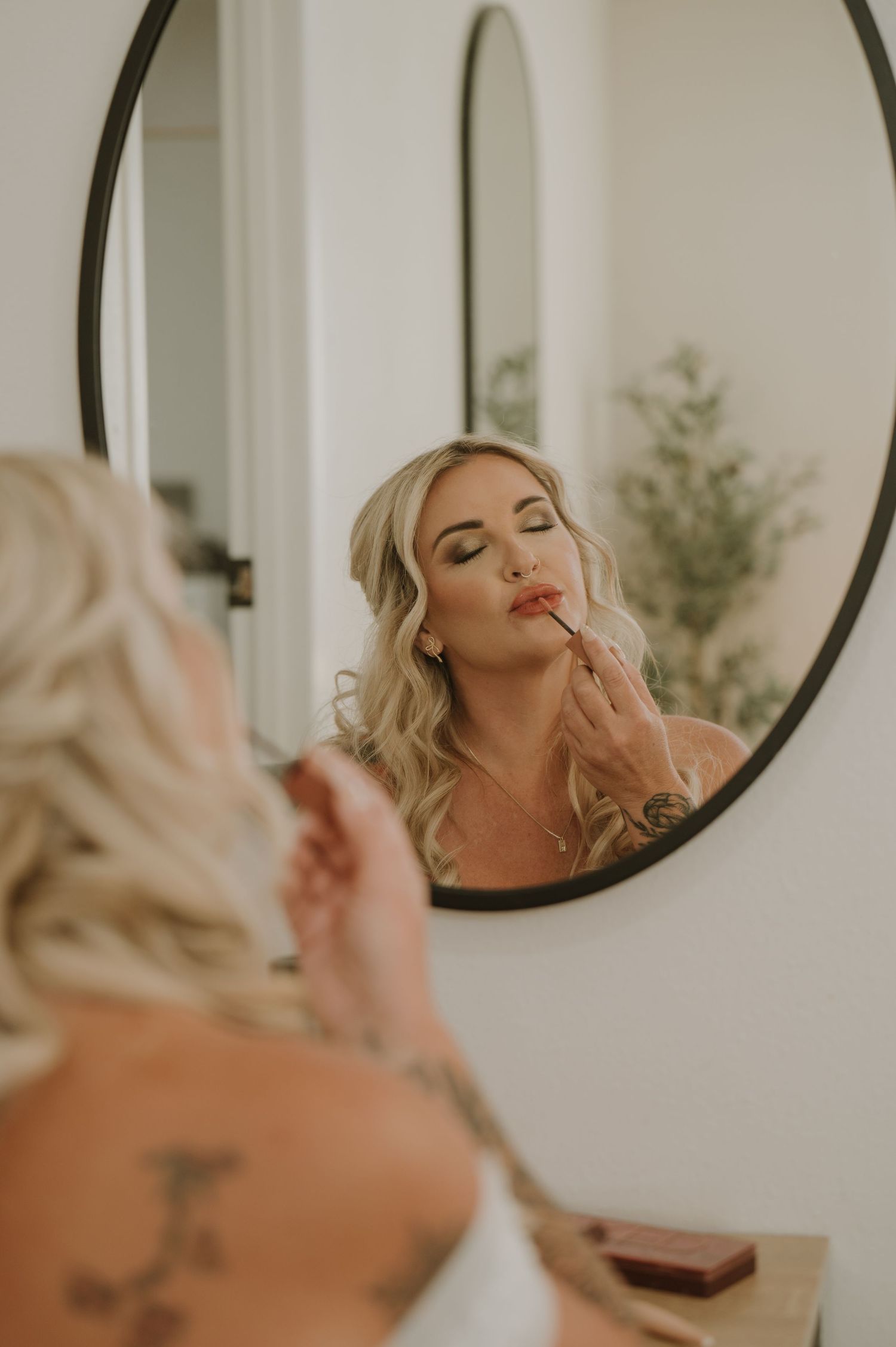 Reflection in round mirror showing bridal makeup preparation.
