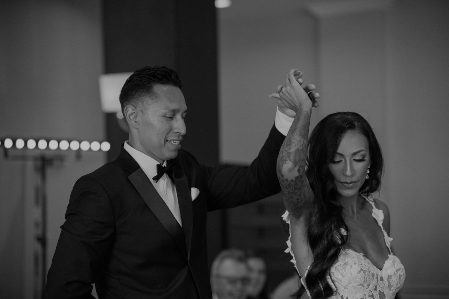 A couple performs their first dance in formal attire at their wedding reception.