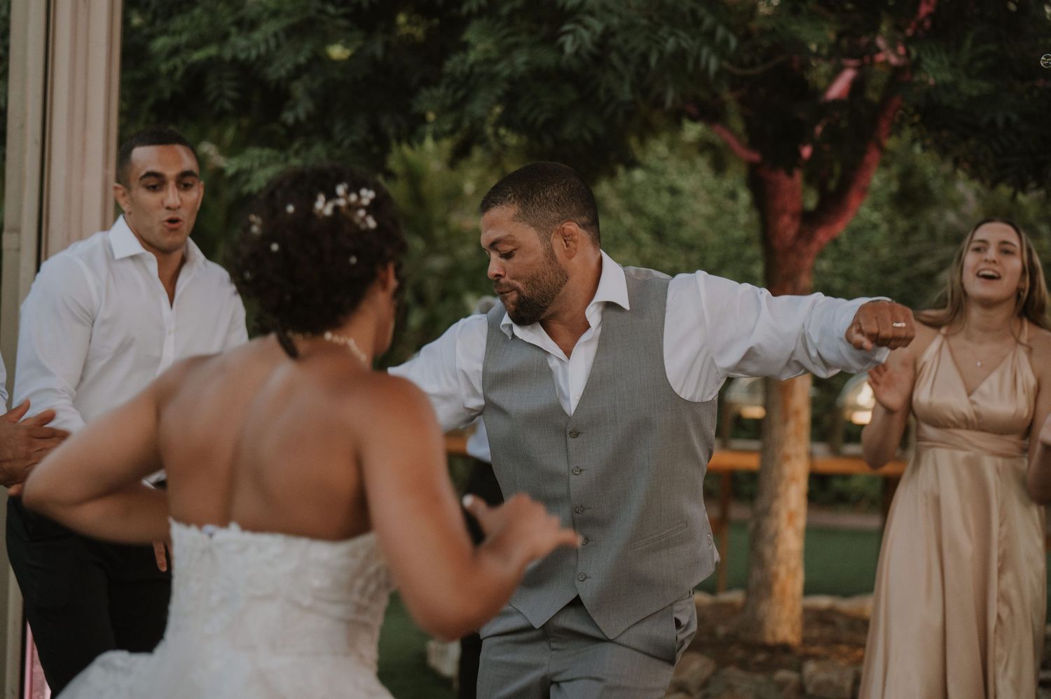 Bride and groom share a joyful dance with guests outdoors at a wedding reception celebration.