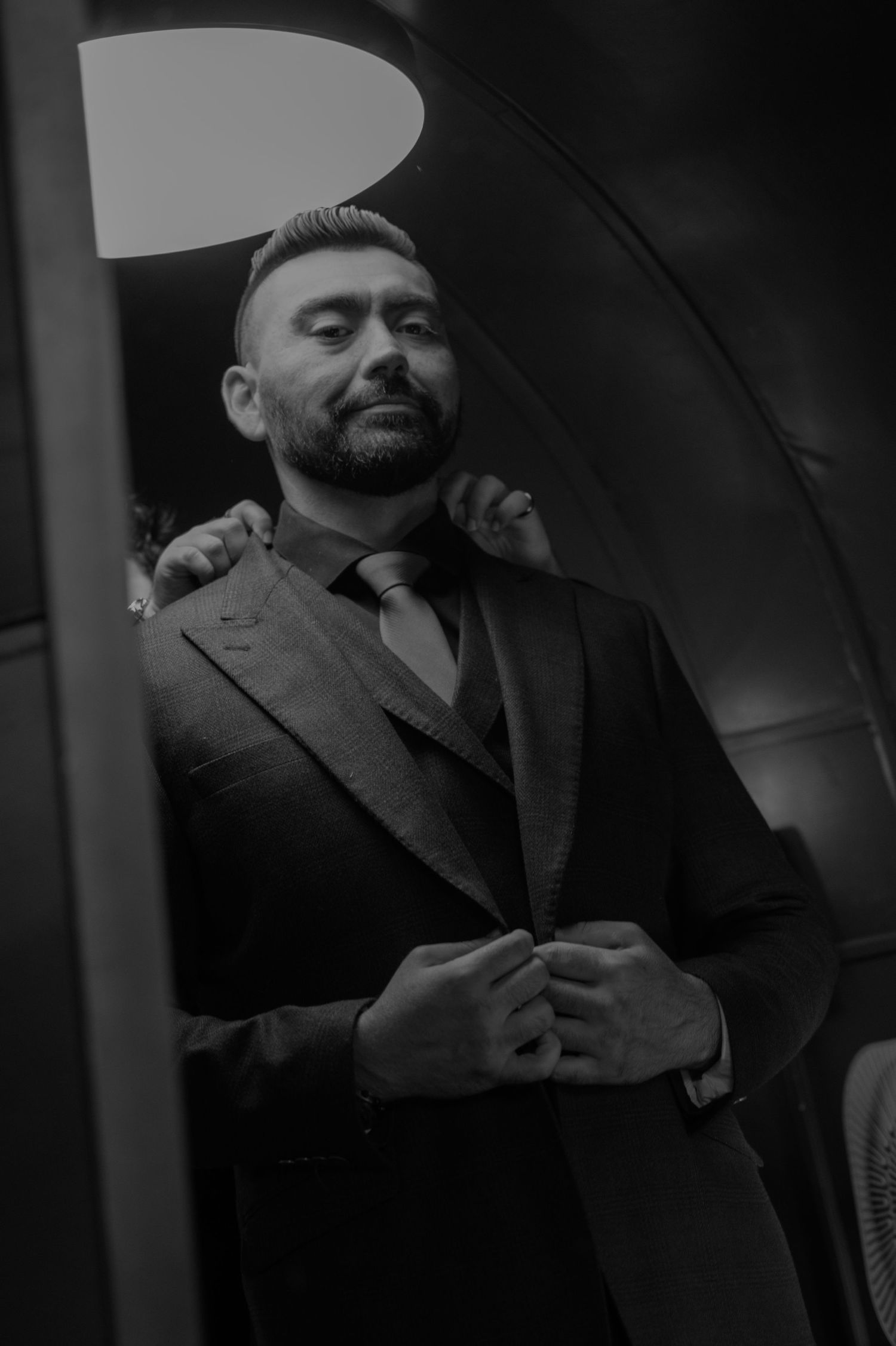 Dramatic black and white portrait of man in formal attire.