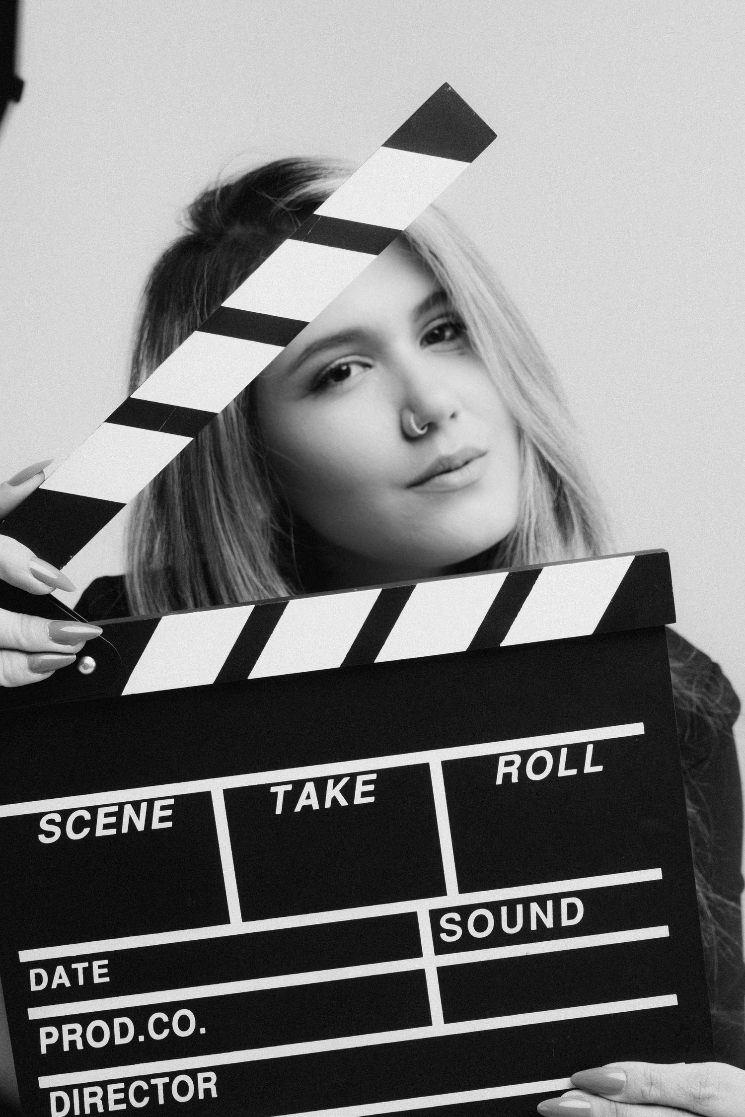 Black and white photo with movie clapperboard in studio setting.