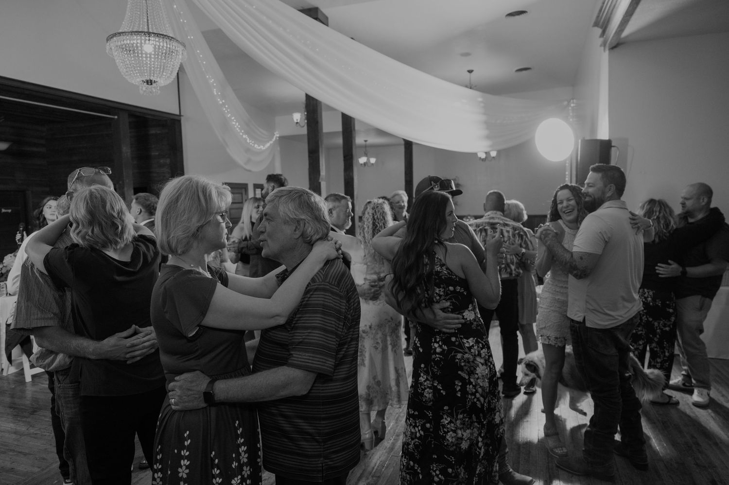 Wedding guests dancing together on the dance floor during an evening reception celebration.
