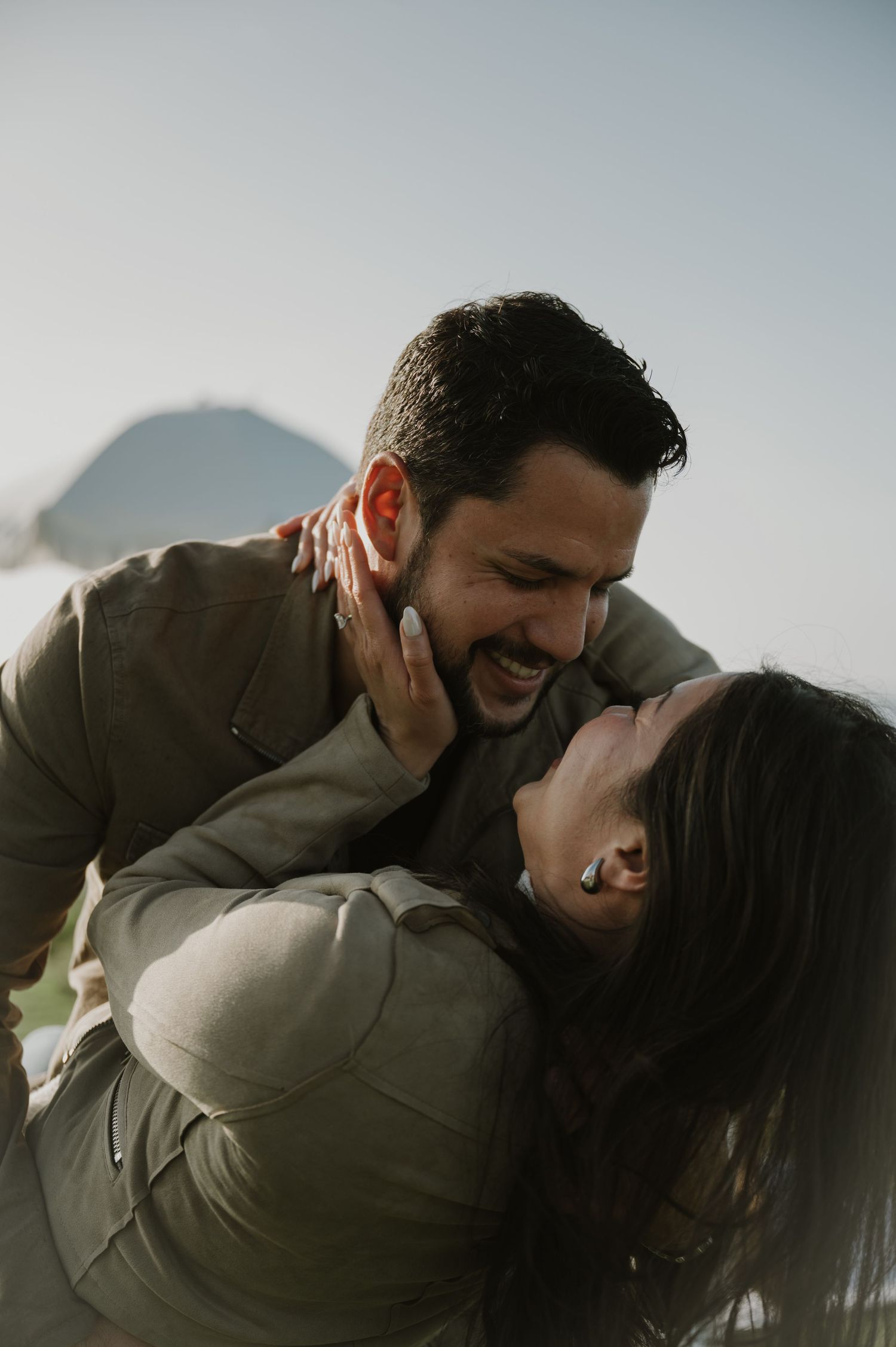 An intimate photoshoot capturing tender moments between a couple against a bright sky.