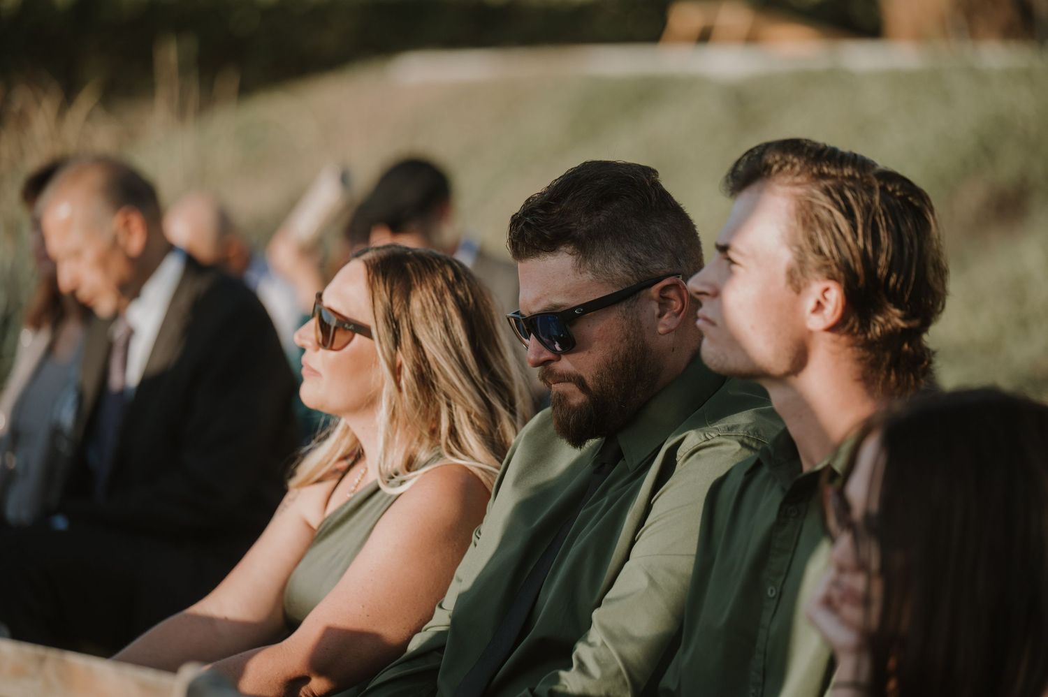 Wedding guests seated outdoors enjoying the ceremony in natural lighting.