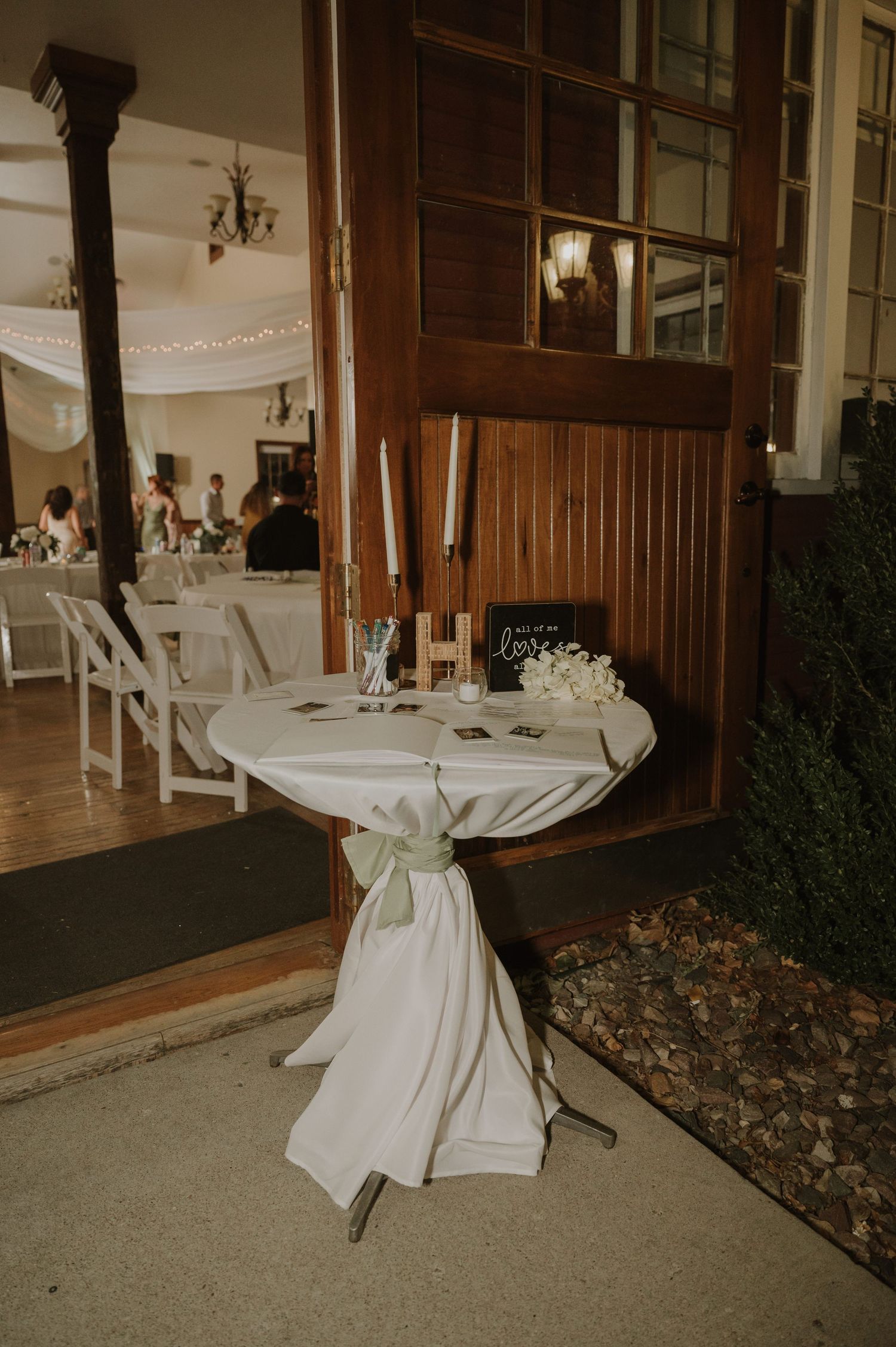 Wedding venue interior with white tablecloths and wooden paneled walls decorated for reception.