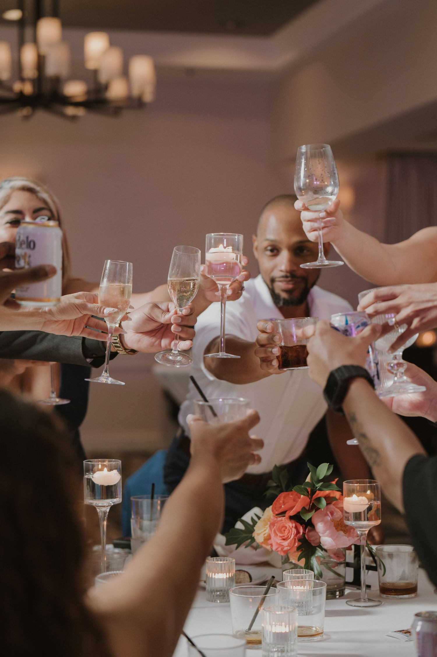 Wedding guests raise glasses in a celebratory toast around a decorated table.
