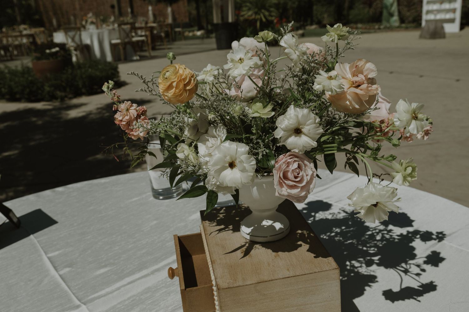 Beautiful wedding centerpiece featuring white, pink, and yellow flowers in a vase on a white linen table.
