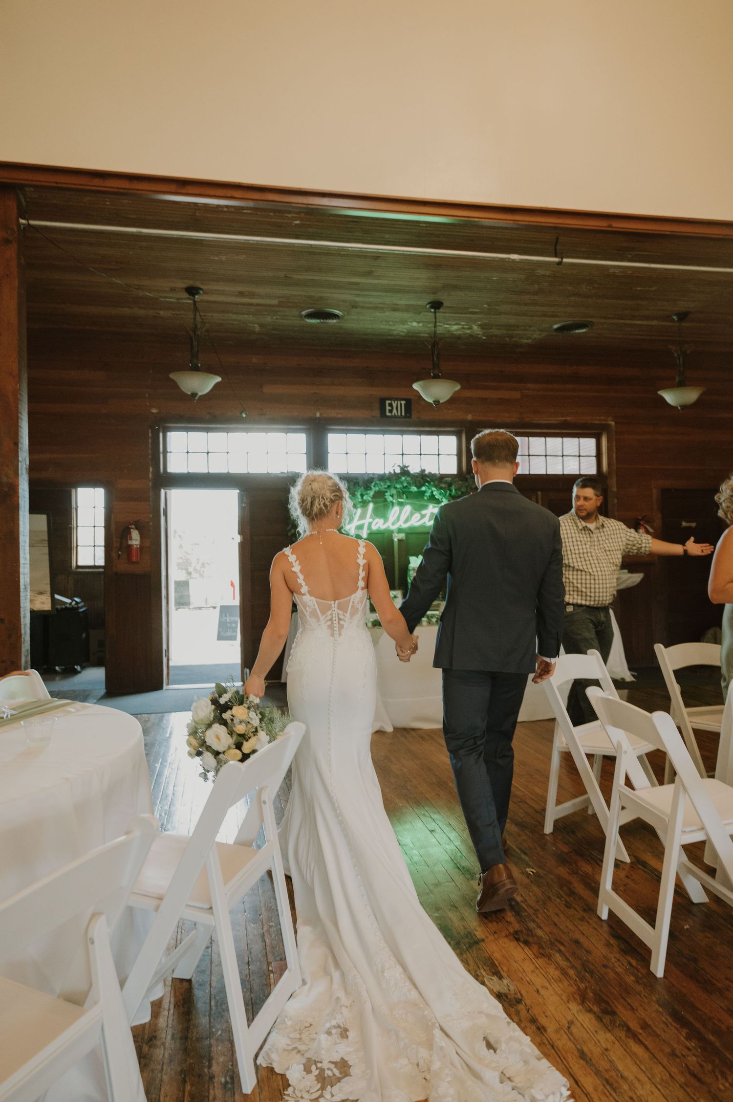 Wedding ceremony setup in a rustic wooden hall with white chairs and natural lighting.