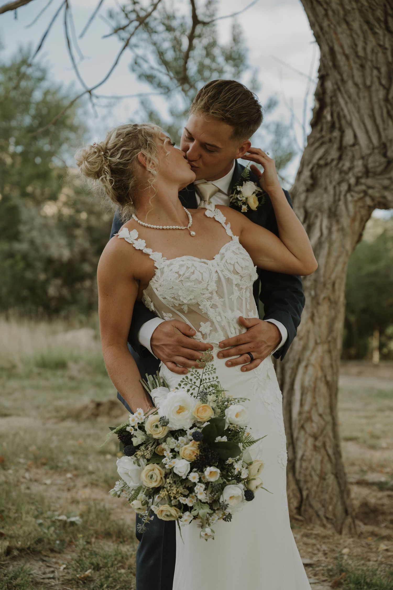 A romantic wedding photoshoot among trees with a beautiful white floral bouquet.