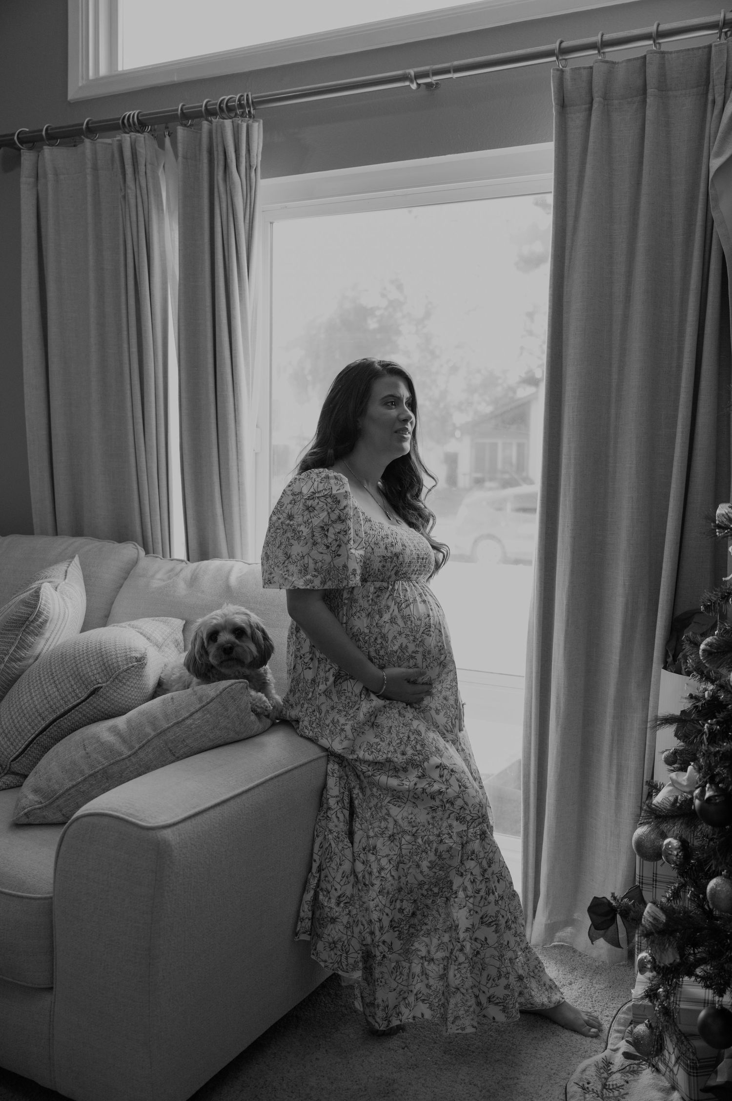 A floral dress silhouette stands by a window with curtains in a bright room.