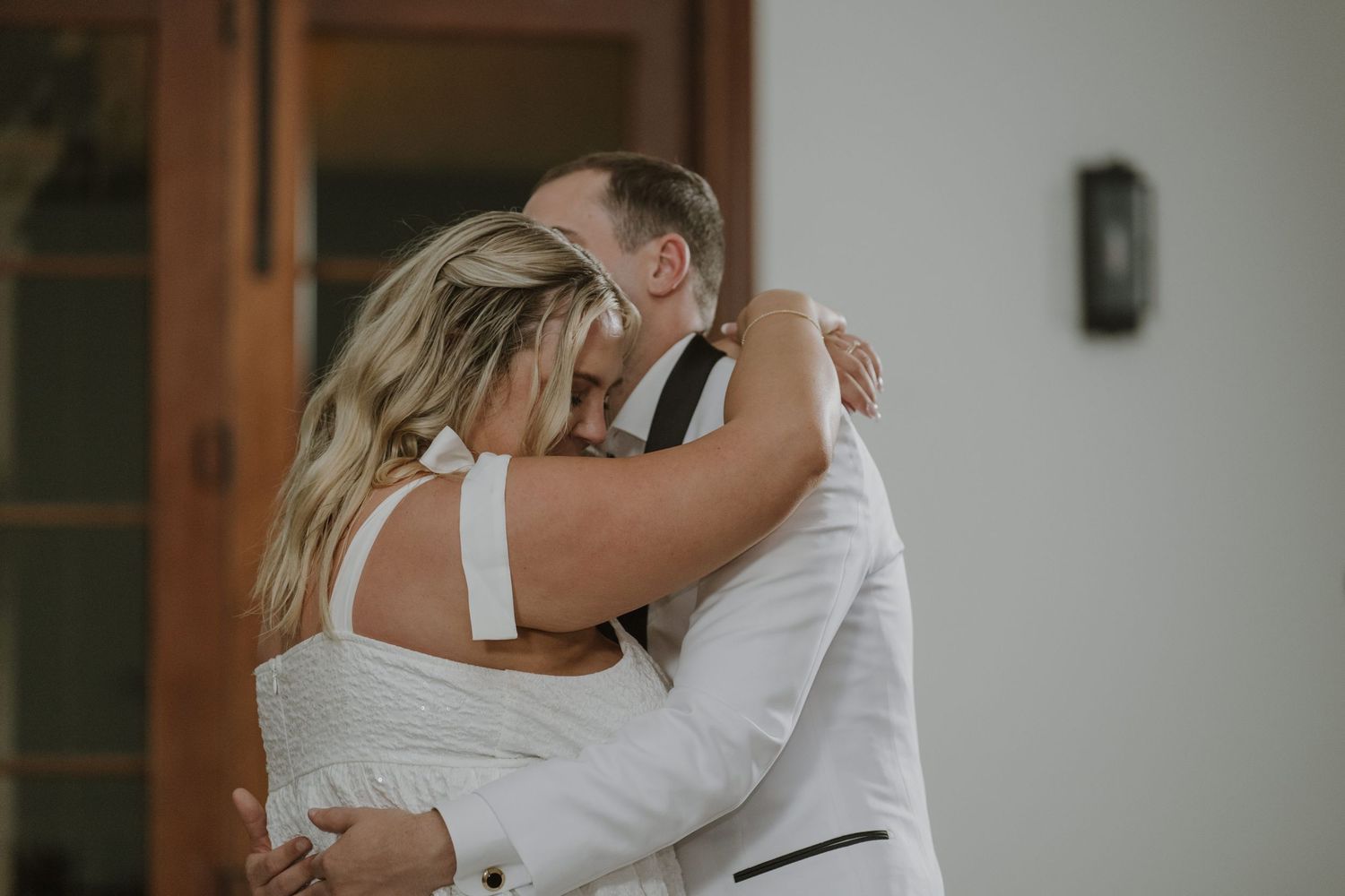 Bride and groom share an emotional first dance embrace at their wedding reception.