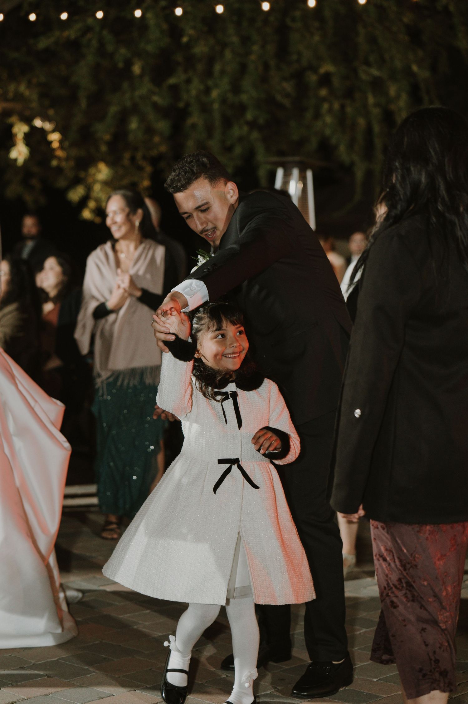 Wedding guests dancing and celebrating at an outdoor evening reception.