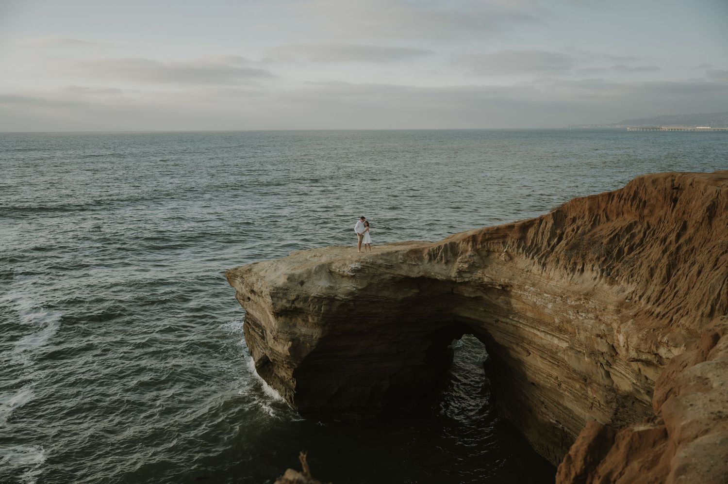 Dramatic coastal cliff overlooking the ocean under cloudy skies.