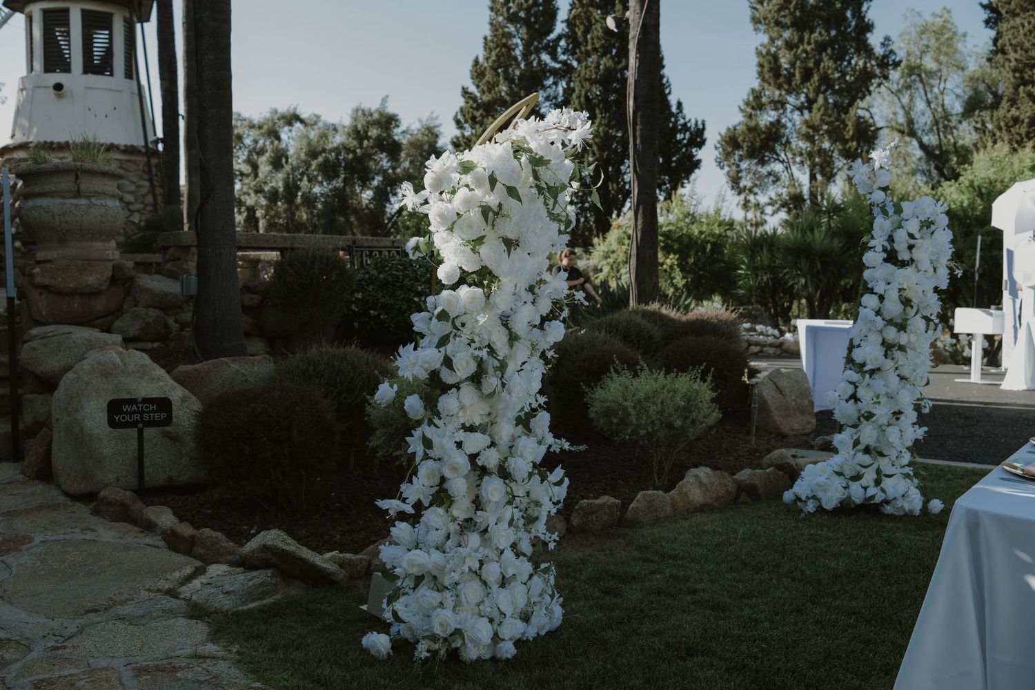 Elegant outdoor wedding ceremony arch adorned with white flowers on green lawn.