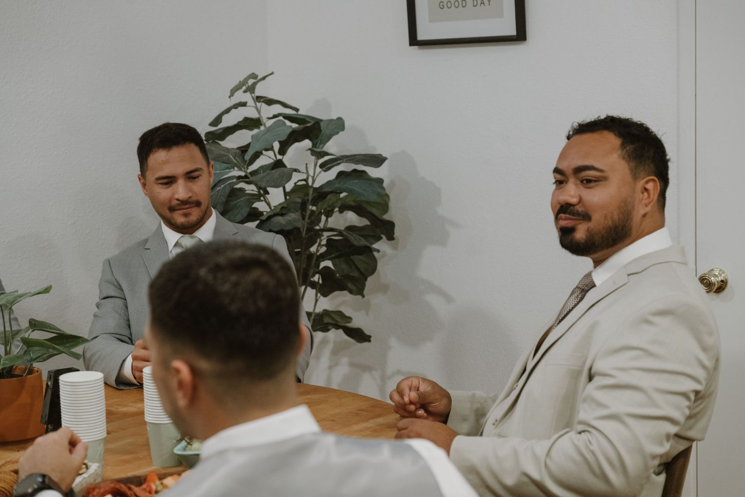 Three men in suits sitting at a wooden table during a formal meeting in a bright modern office.