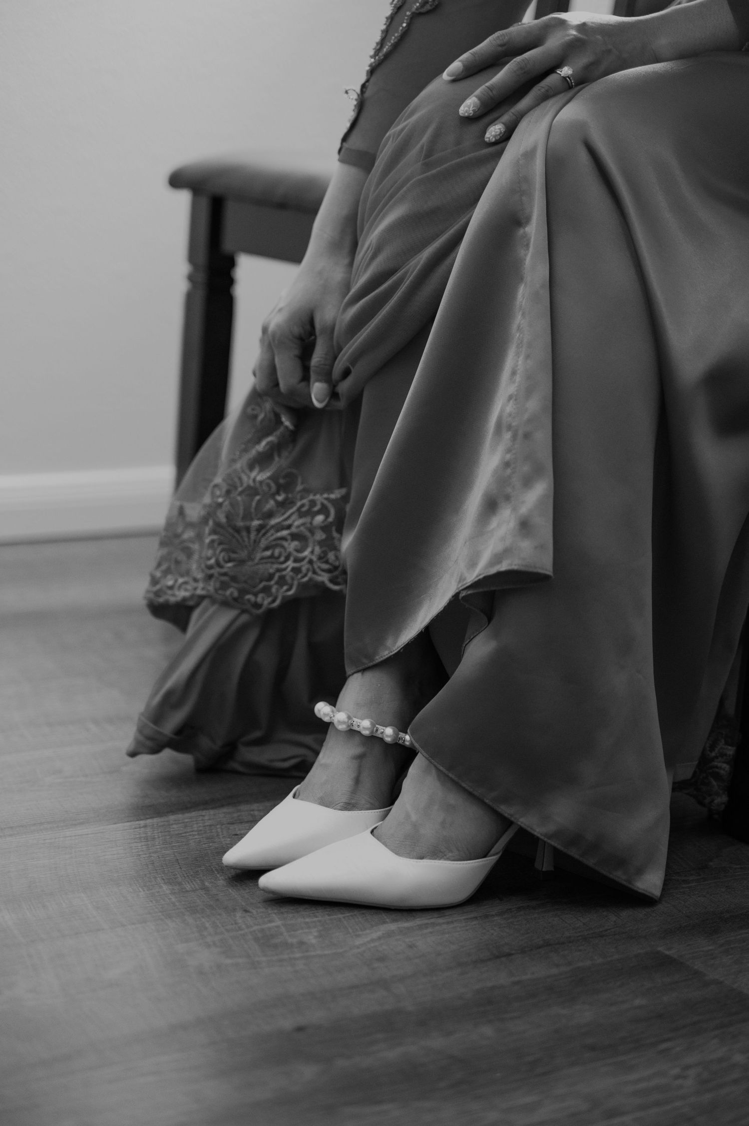 Black and white detail shot of bride's feet in white shoes with pearl anklet.