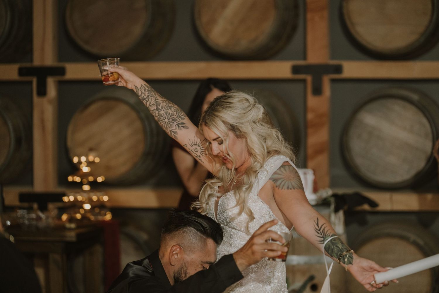 Celebratory gathering in a wine barrel room with festive lighting.