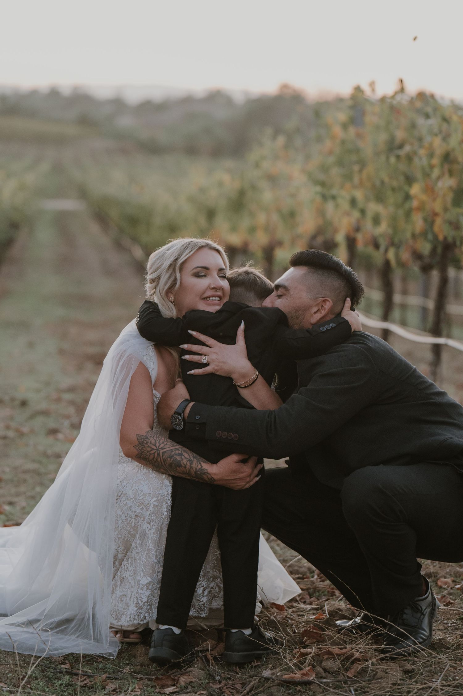 A romantic wedding photo shoot in a vineyard shows a couple laying on the ground at sunset.