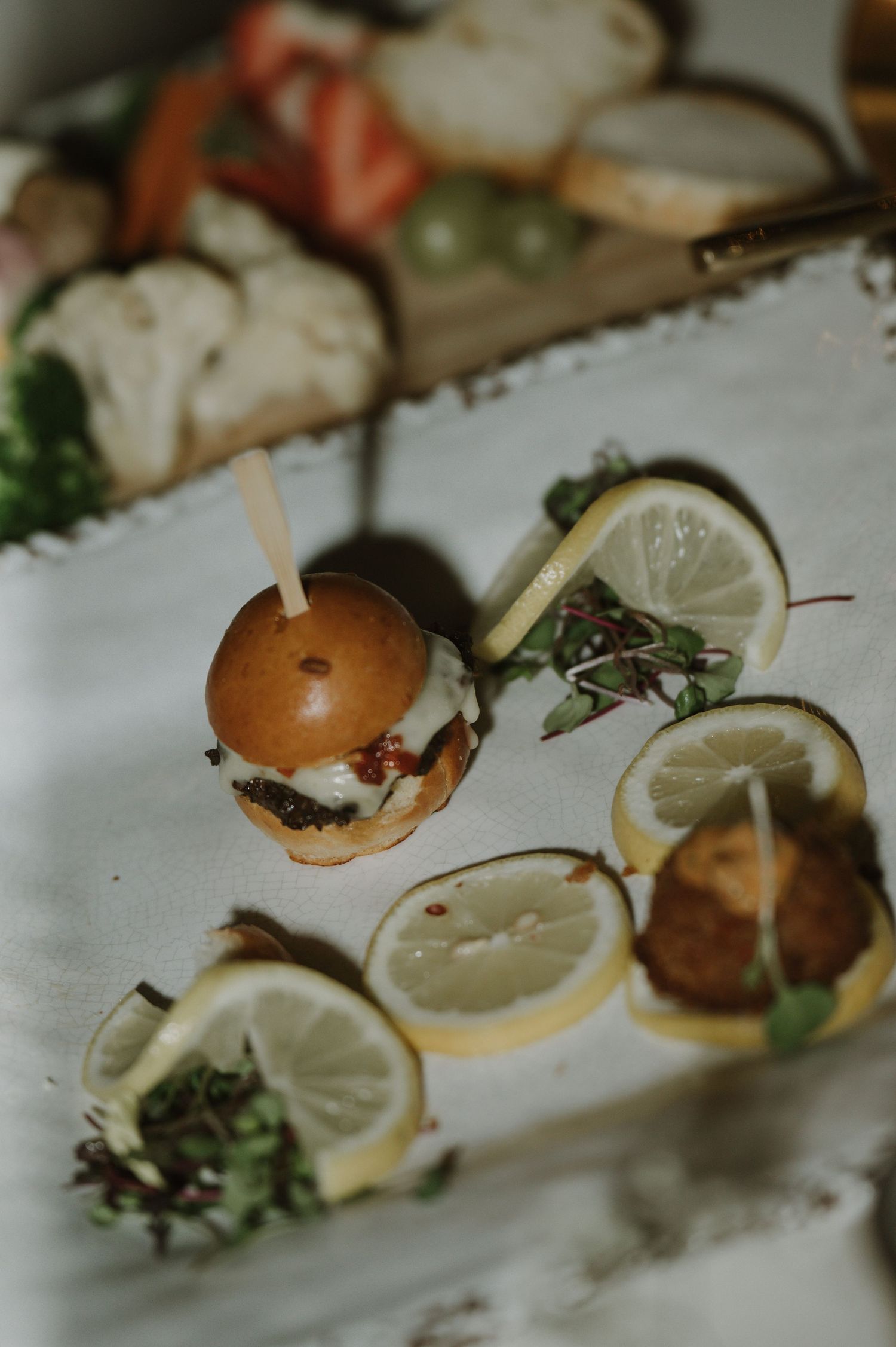 Artfully plated appetizers with lemon garnish and microgreens on white plates.