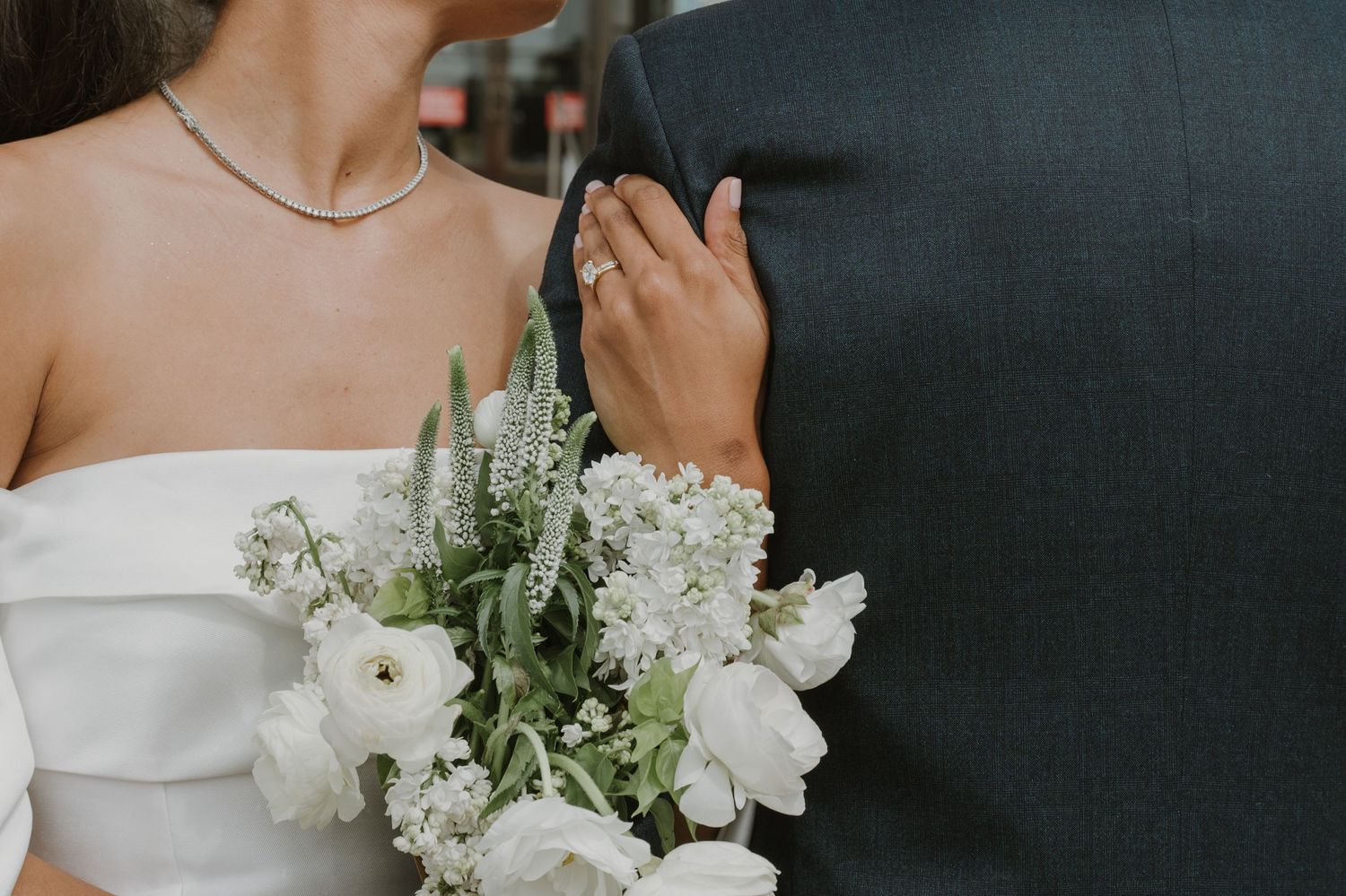 Elegant white bridal bouquet with roses against formal black attire.