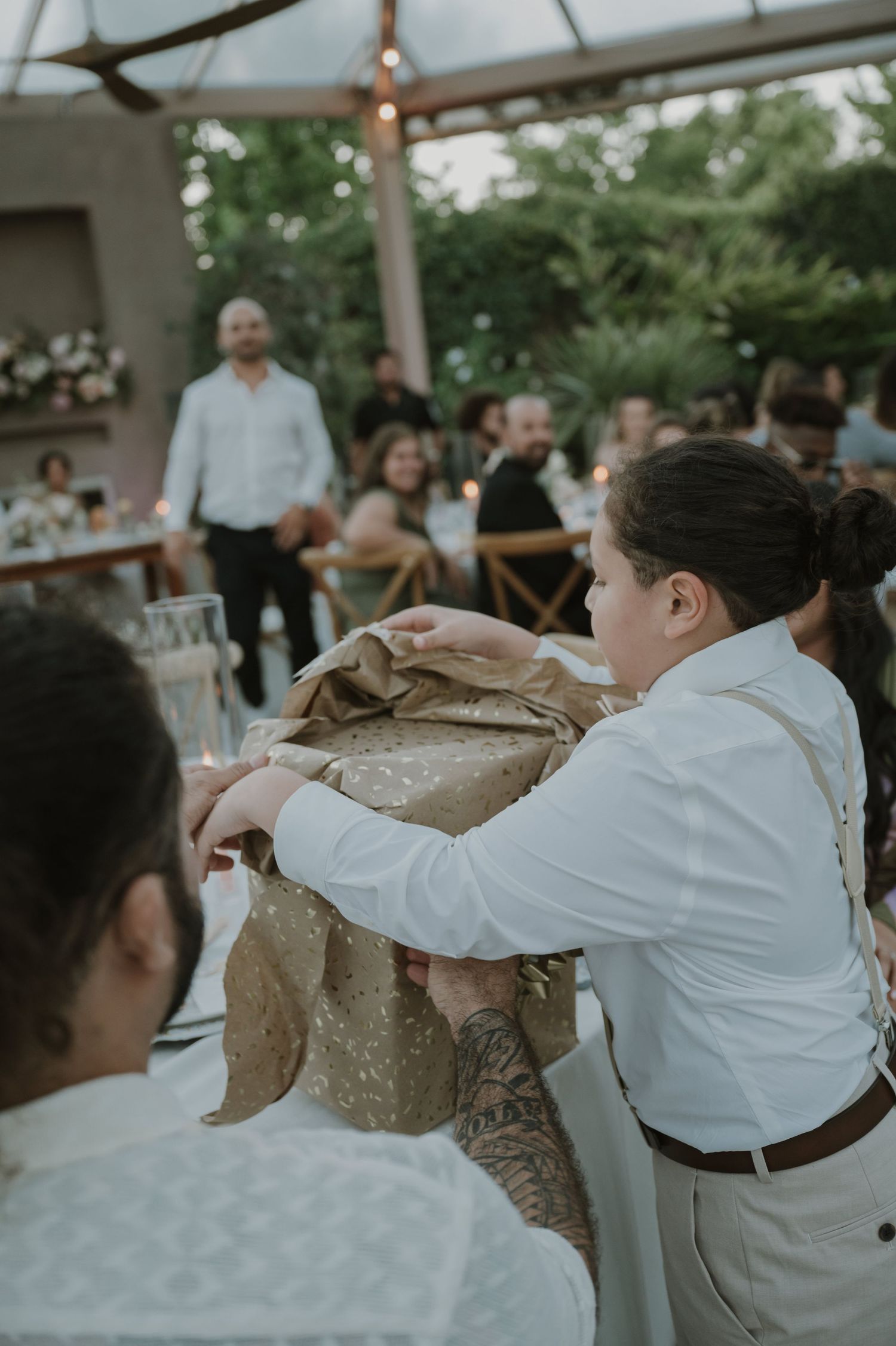Wedding staff member carefully unwrapping a gift at an elegant outdoor wedding reception.