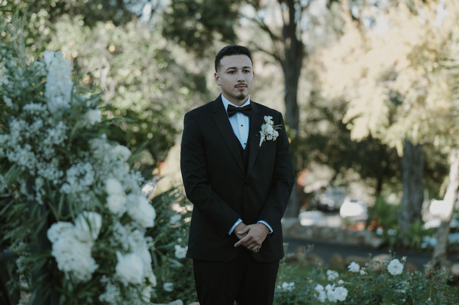 Elegant outdoor wedding ceremony setup with white floral decorations.