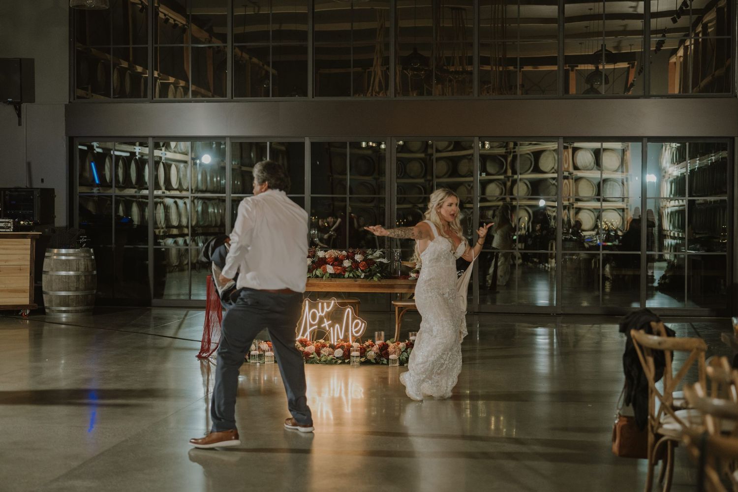 Dark interior of rustic wedding venue with barrels and ambient lighting.