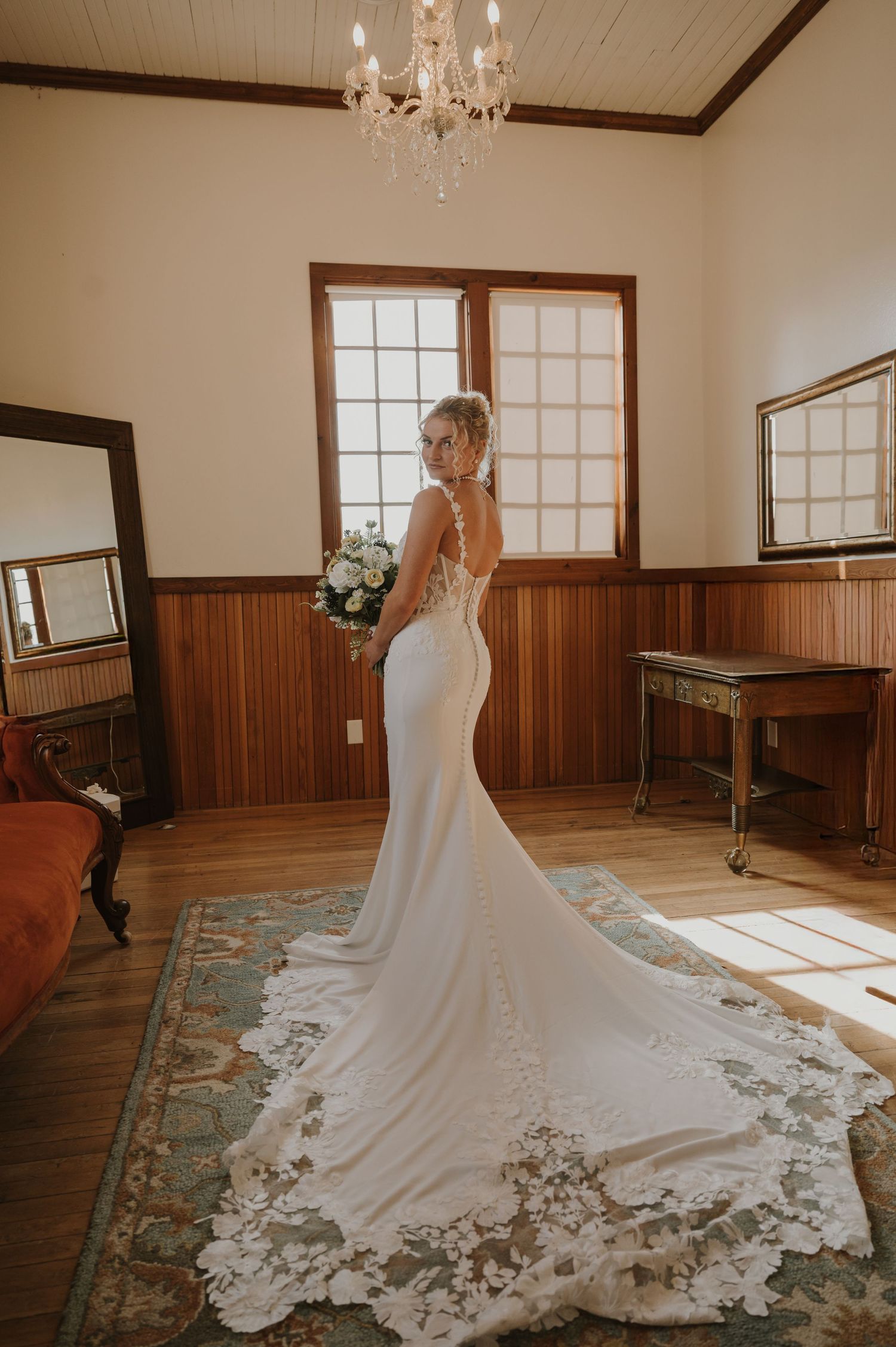 Stunning lace wedding gown with cathedral train displayed in a wood-paneled room.