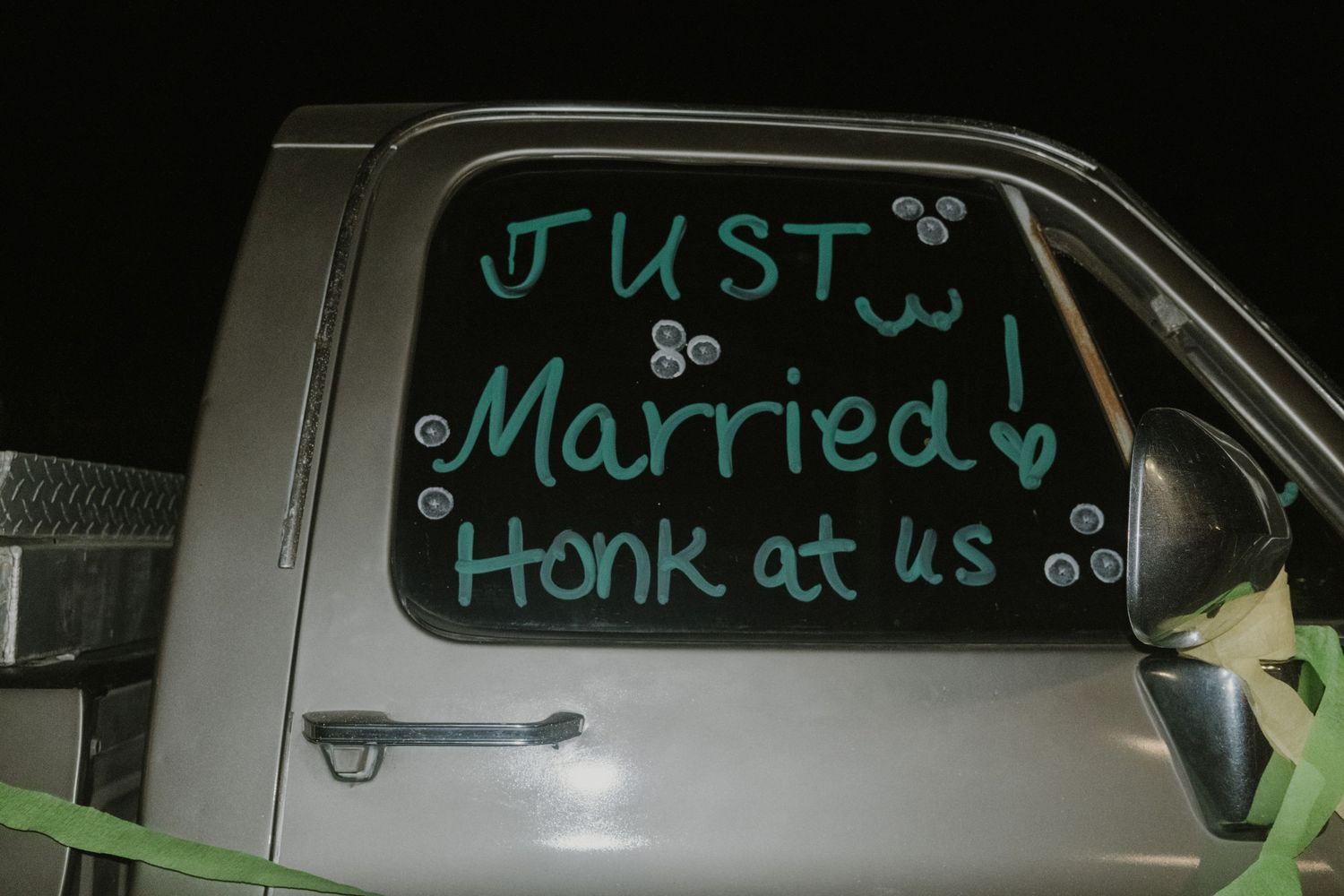 Car windows decorated with 'Just Married' text in turquoise writing for a wedding celebration.
