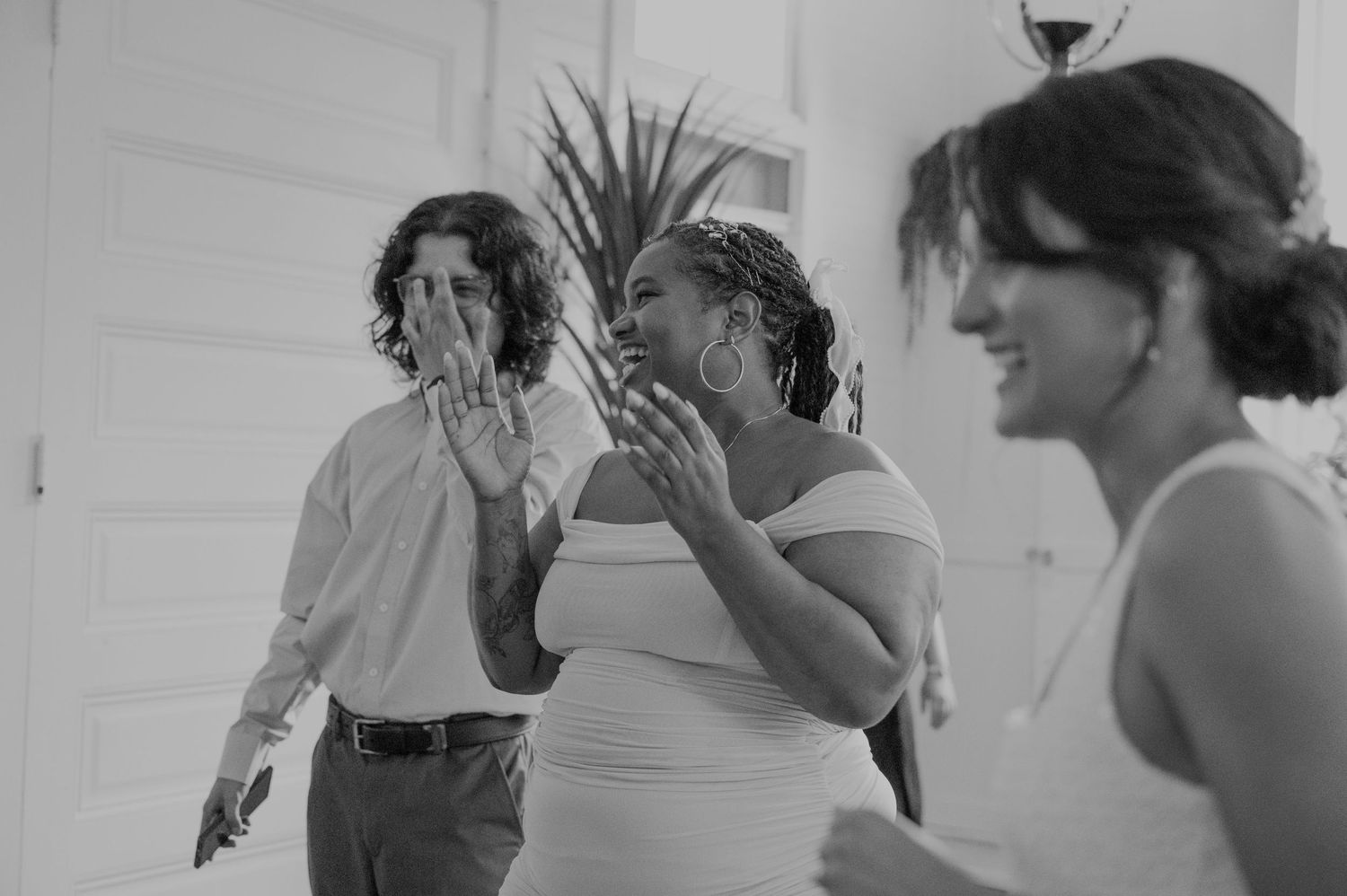 Black and white photo of emotional wedding guests reacting with surprise and joy during bridal reveal.