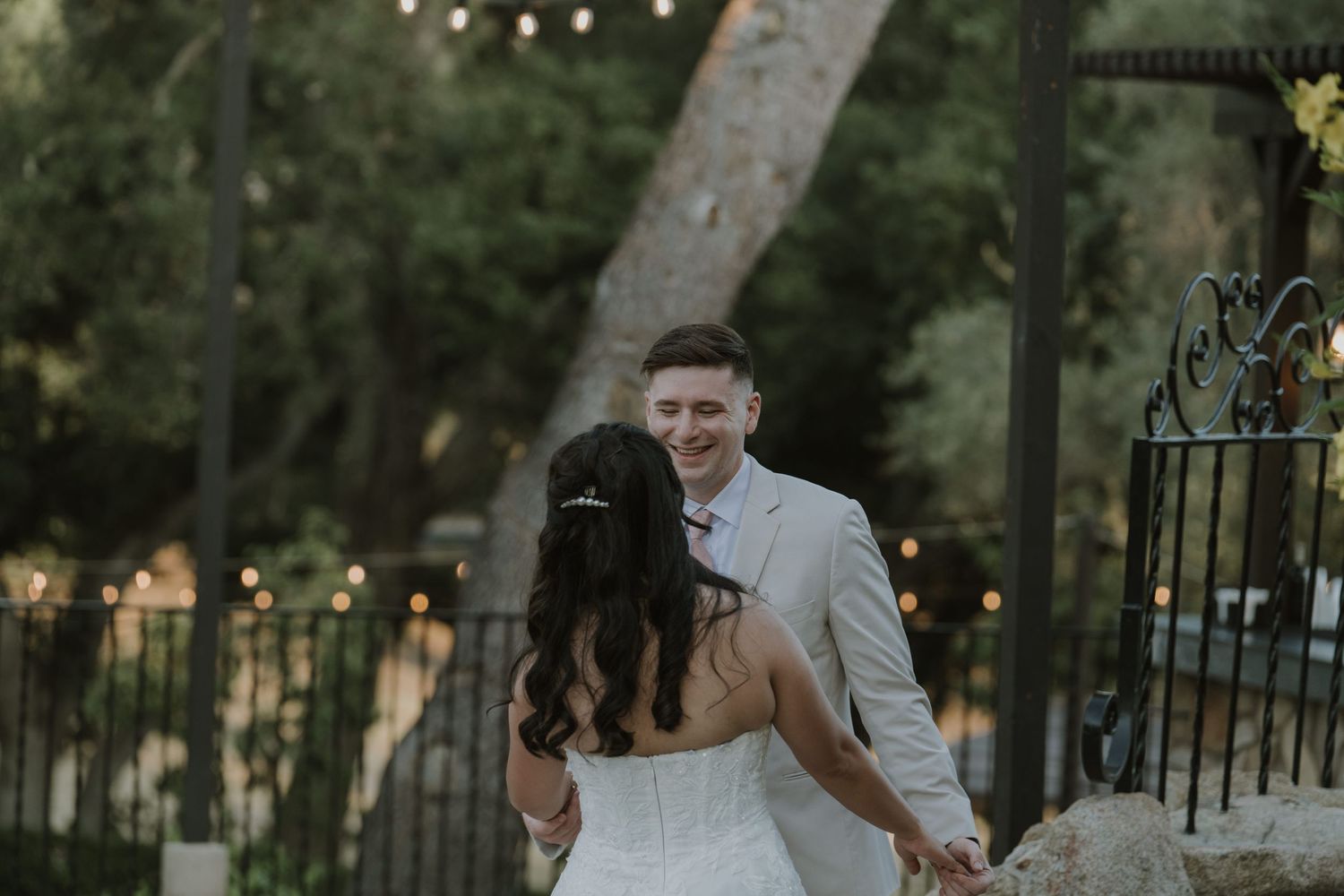 Bride and groom share a romantic first dance outdoors at a garden wedding venue with string lights.