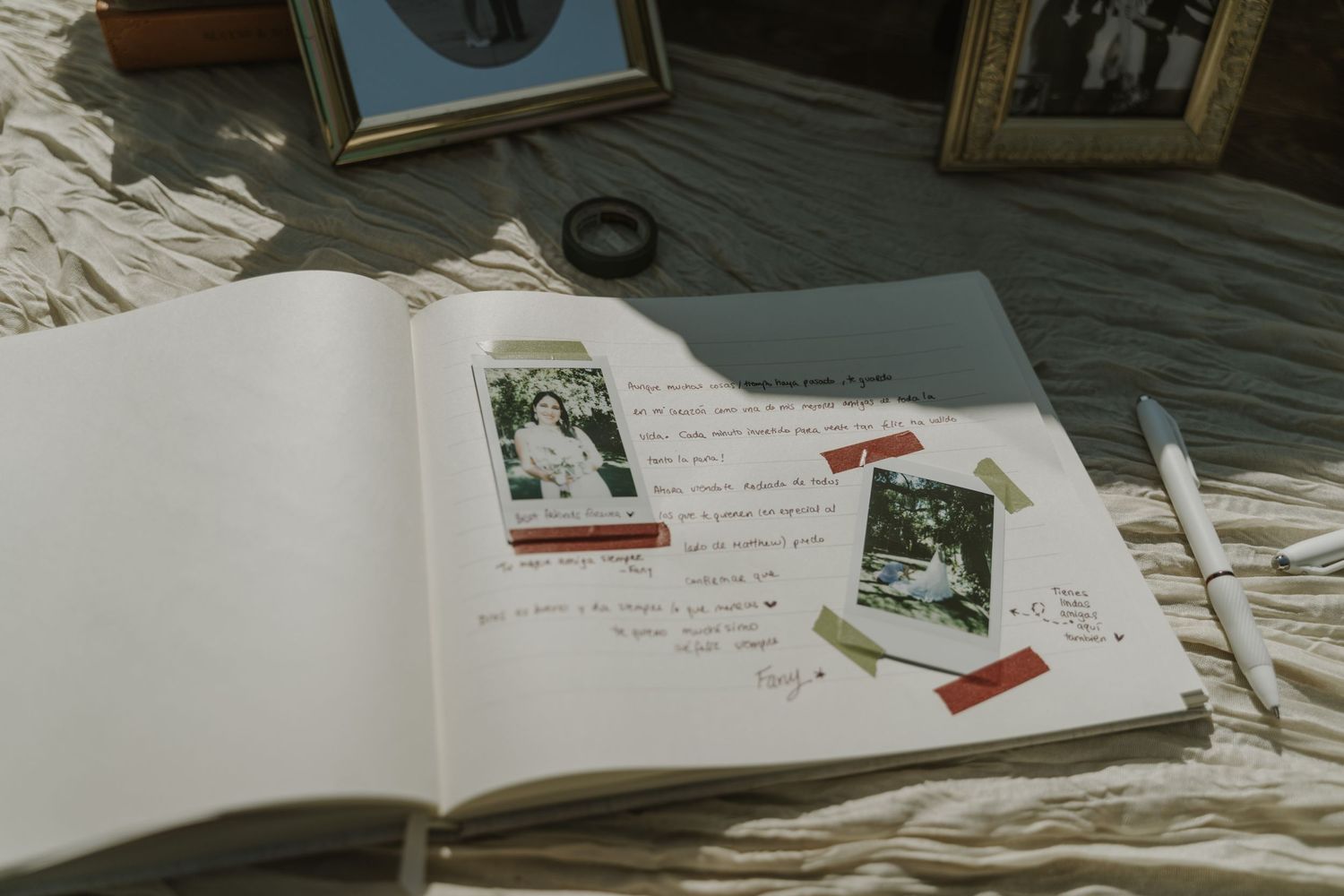 Open scrapbook journal with taped polaroid photos and handwritten notes on a textured white surface.