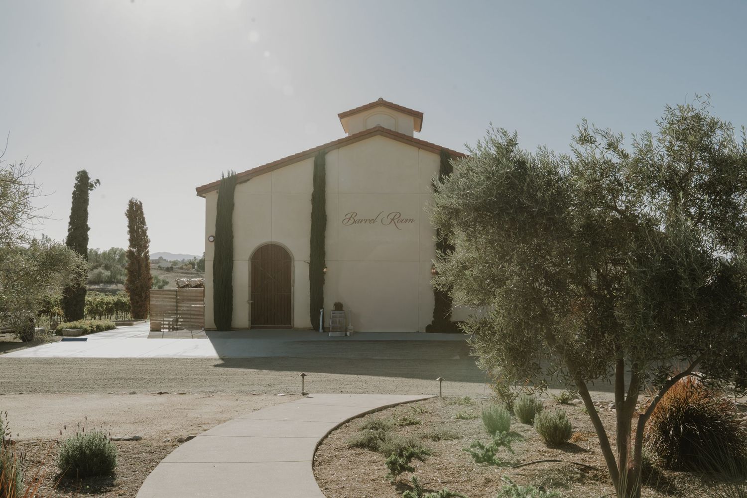 Mediterranean-style winery buildings with white stucco walls and terracotta roofs in a desert landscape.