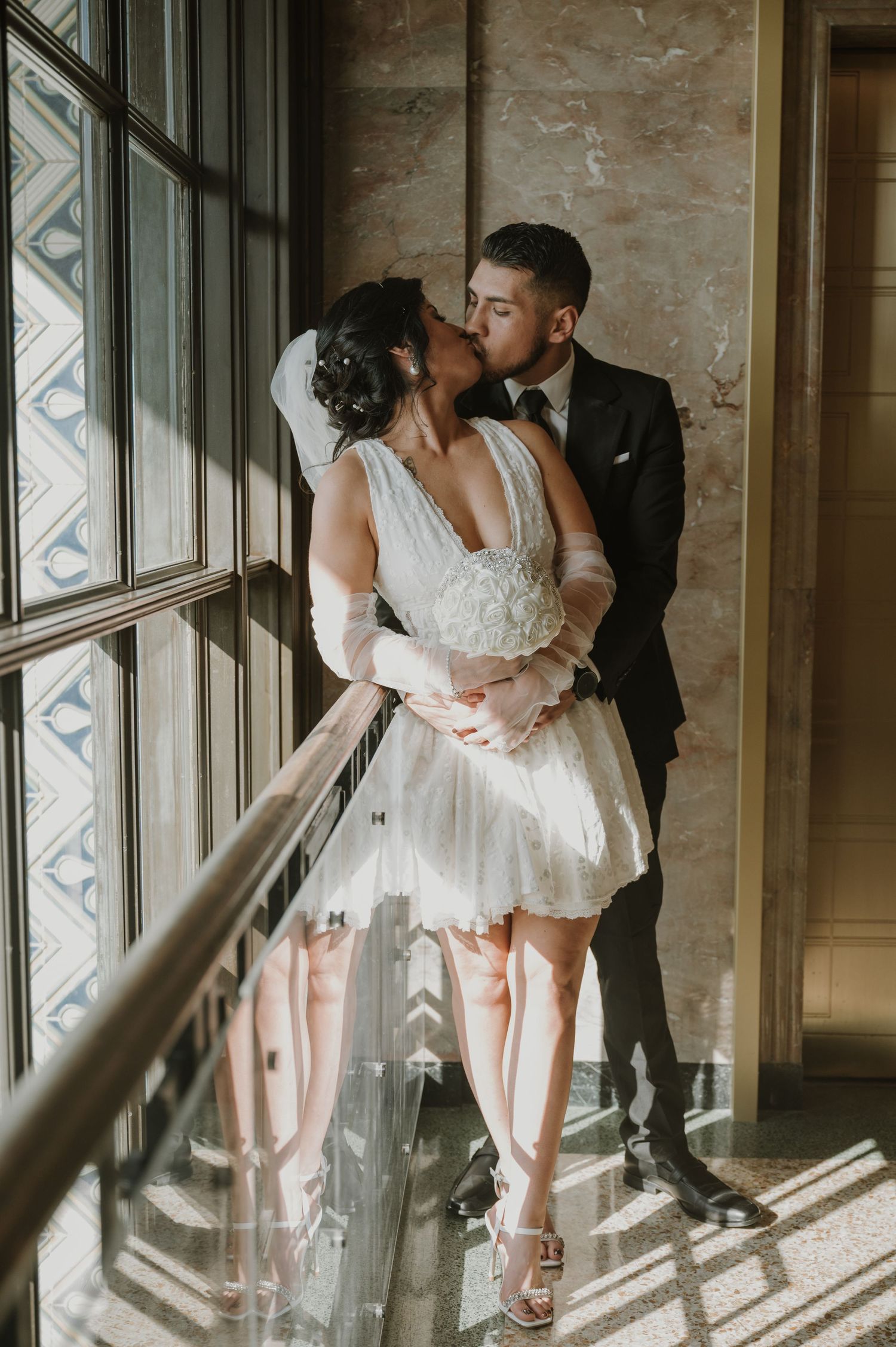 Sunlit wedding portraits by vintage windows show romantic moments between newlyweds.