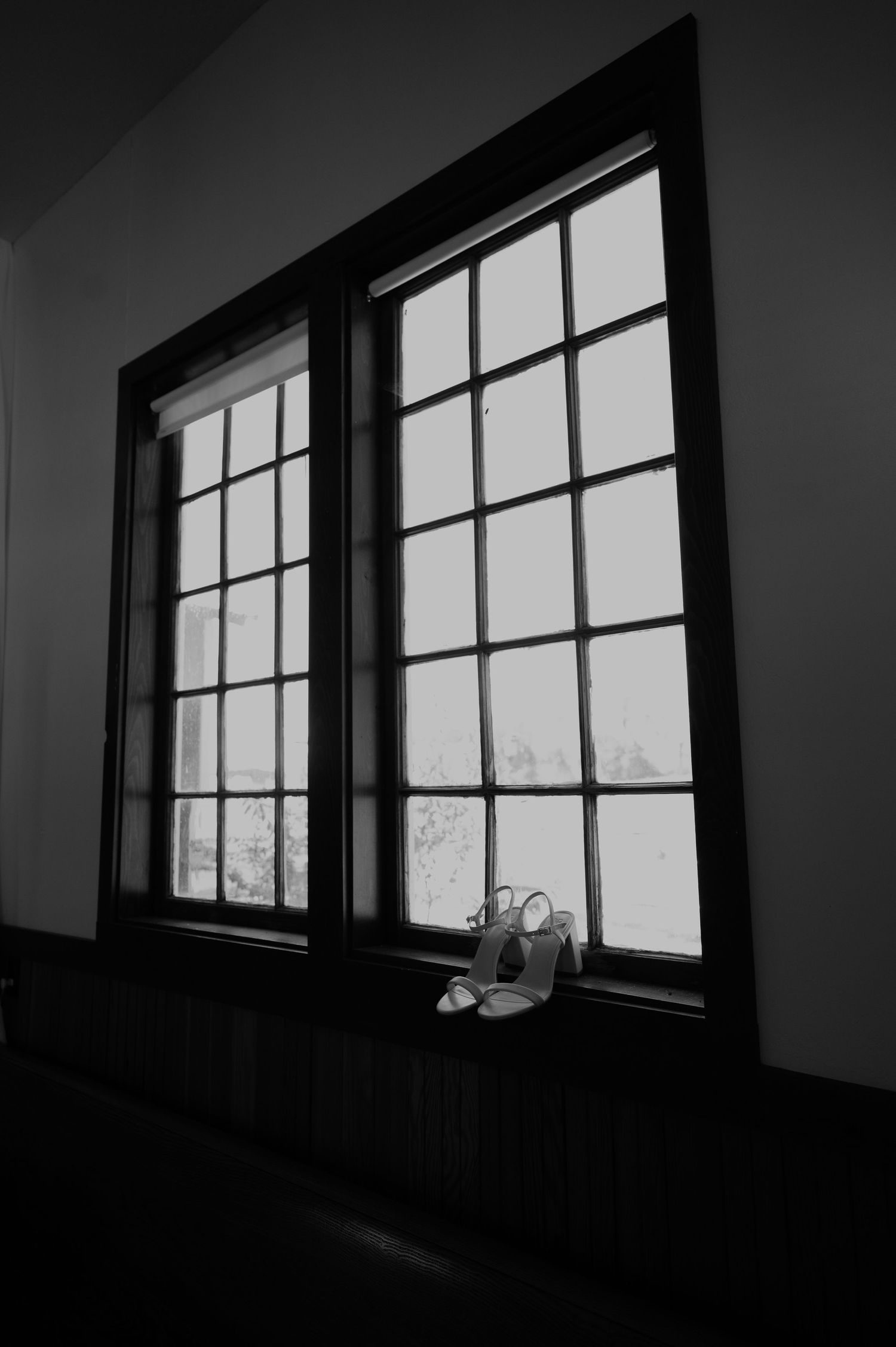 Black and white view of multiple windows in a dark room creating geometric shadows.