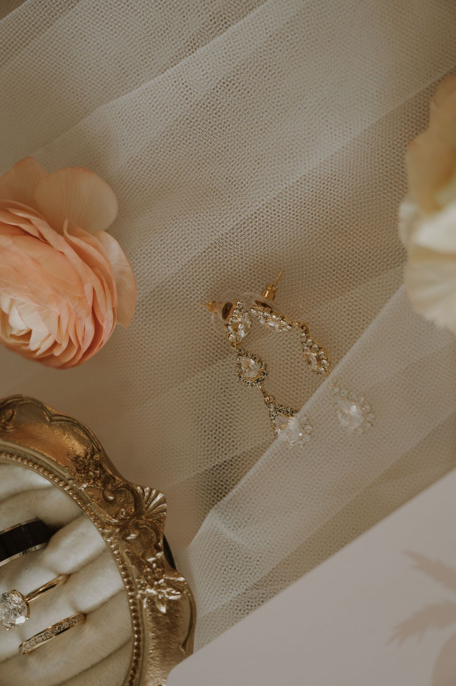 Wedding accessories including delicate veil and gold jewelry on light fabric.