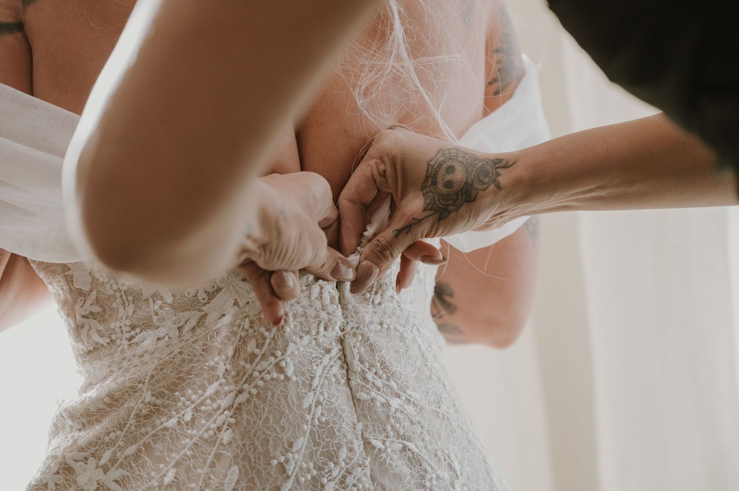 Close-up details of lacing up an intricate white wedding dress.
