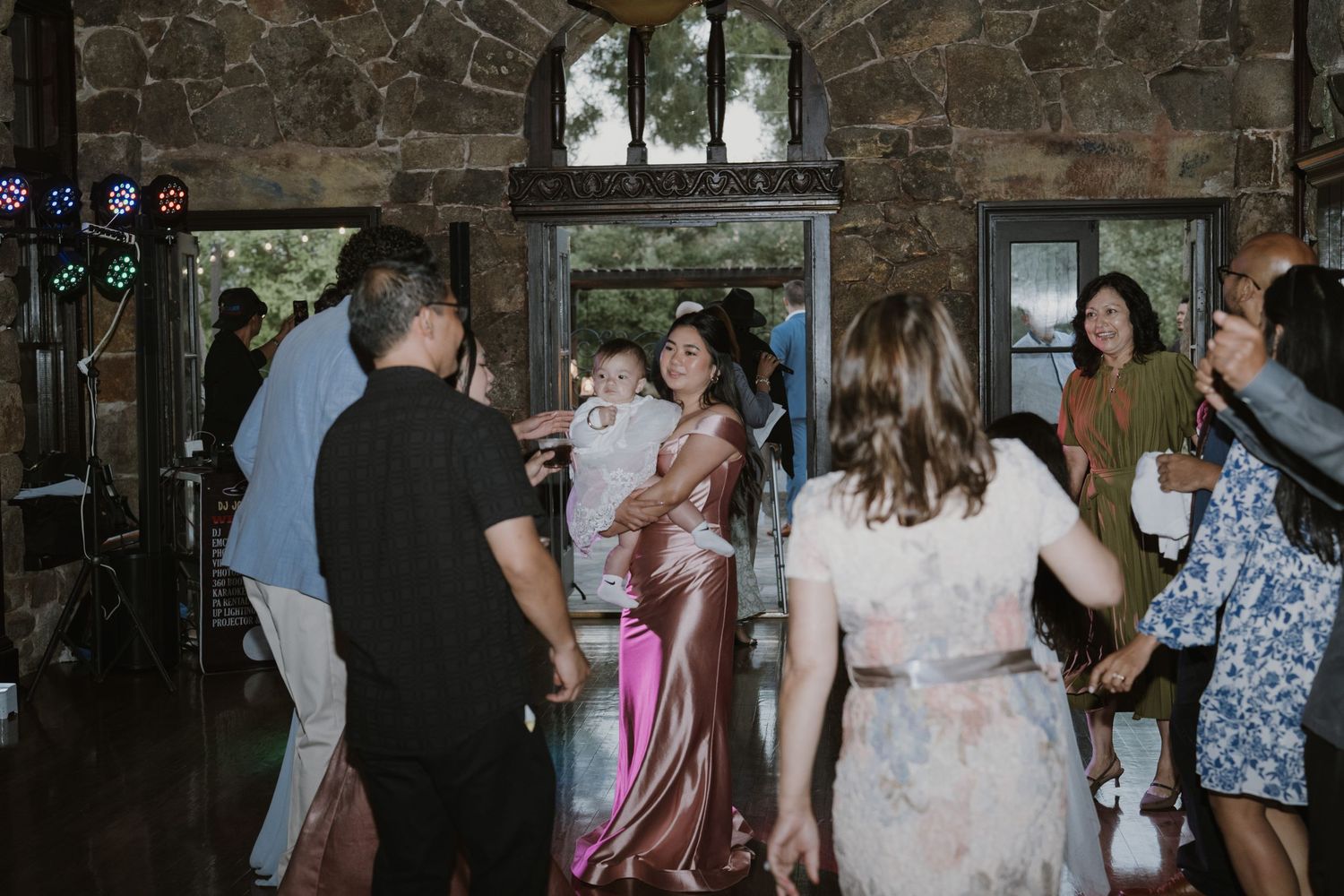 Guests dancing and celebrating at a wedding reception in a rustic stone venue with warm ambient lighting.